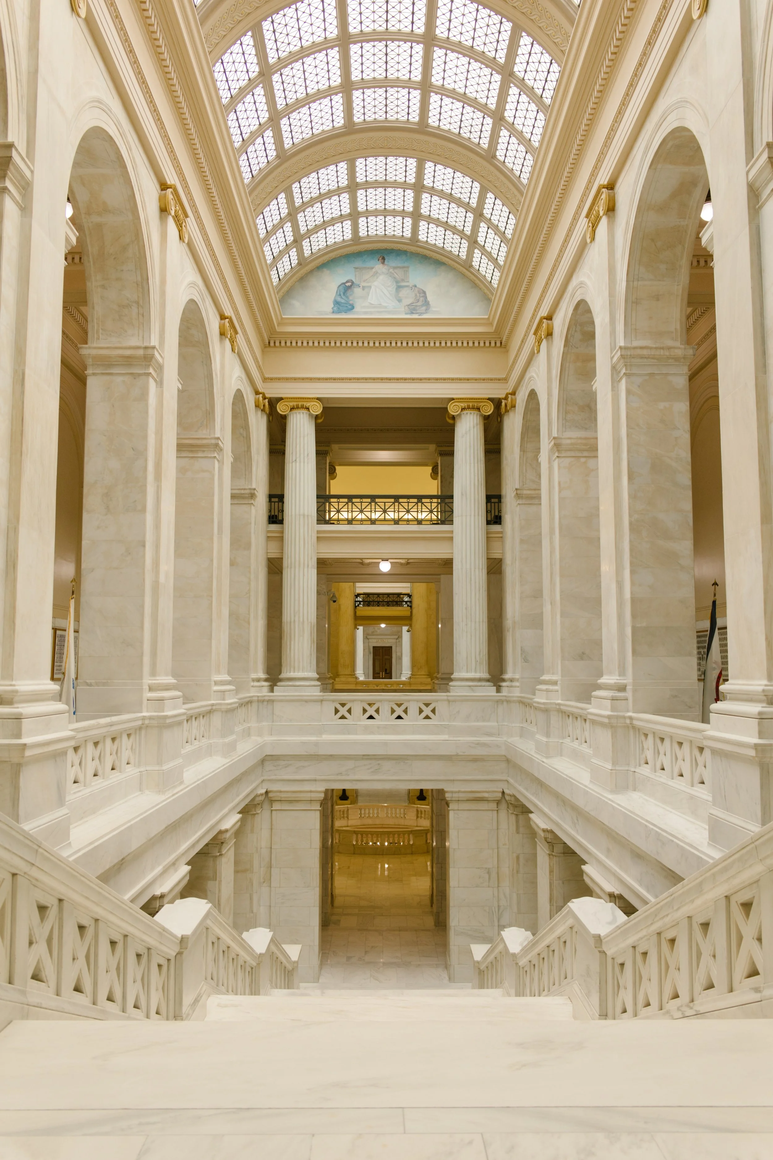 Empty view of the historic Little Rock courthouse showcasing marble staircases, columns, and vaulted skylights.