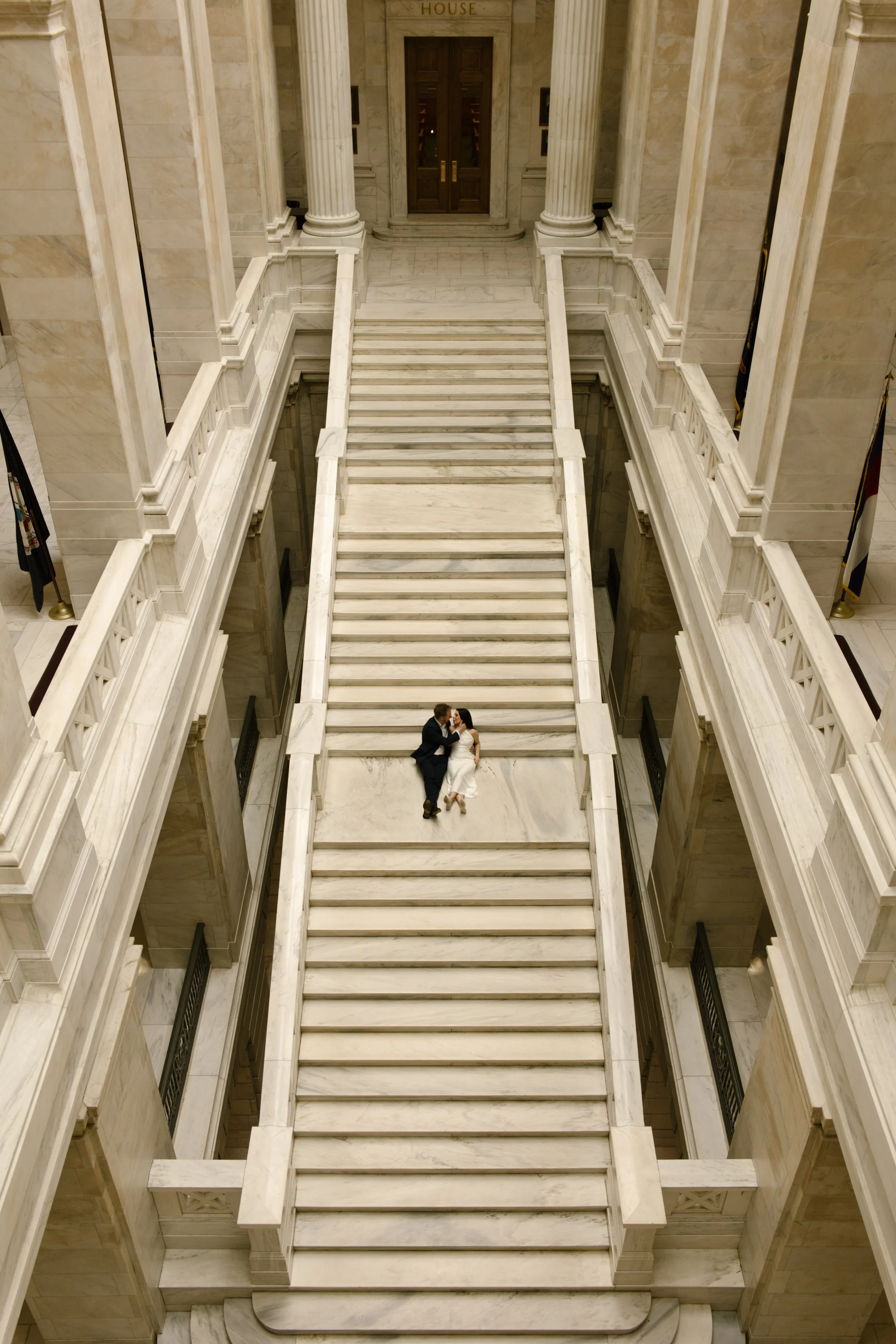 Overhead view of a couple sitting together on the dramatic central staircase of the Little Rock courthouse.