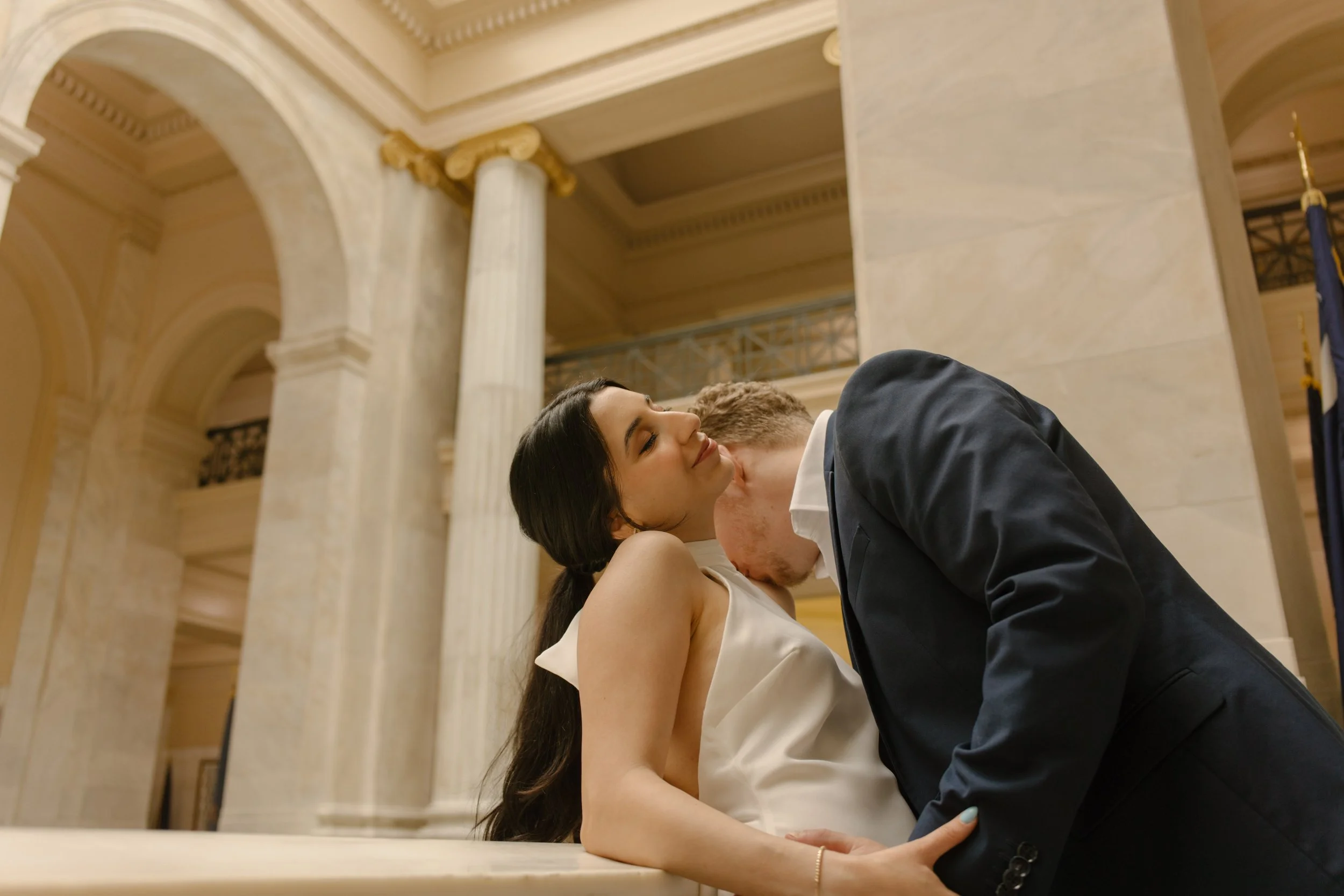 Intimate portrait of the couple leaning against the staircase railing inside the Little Rock courthouse.