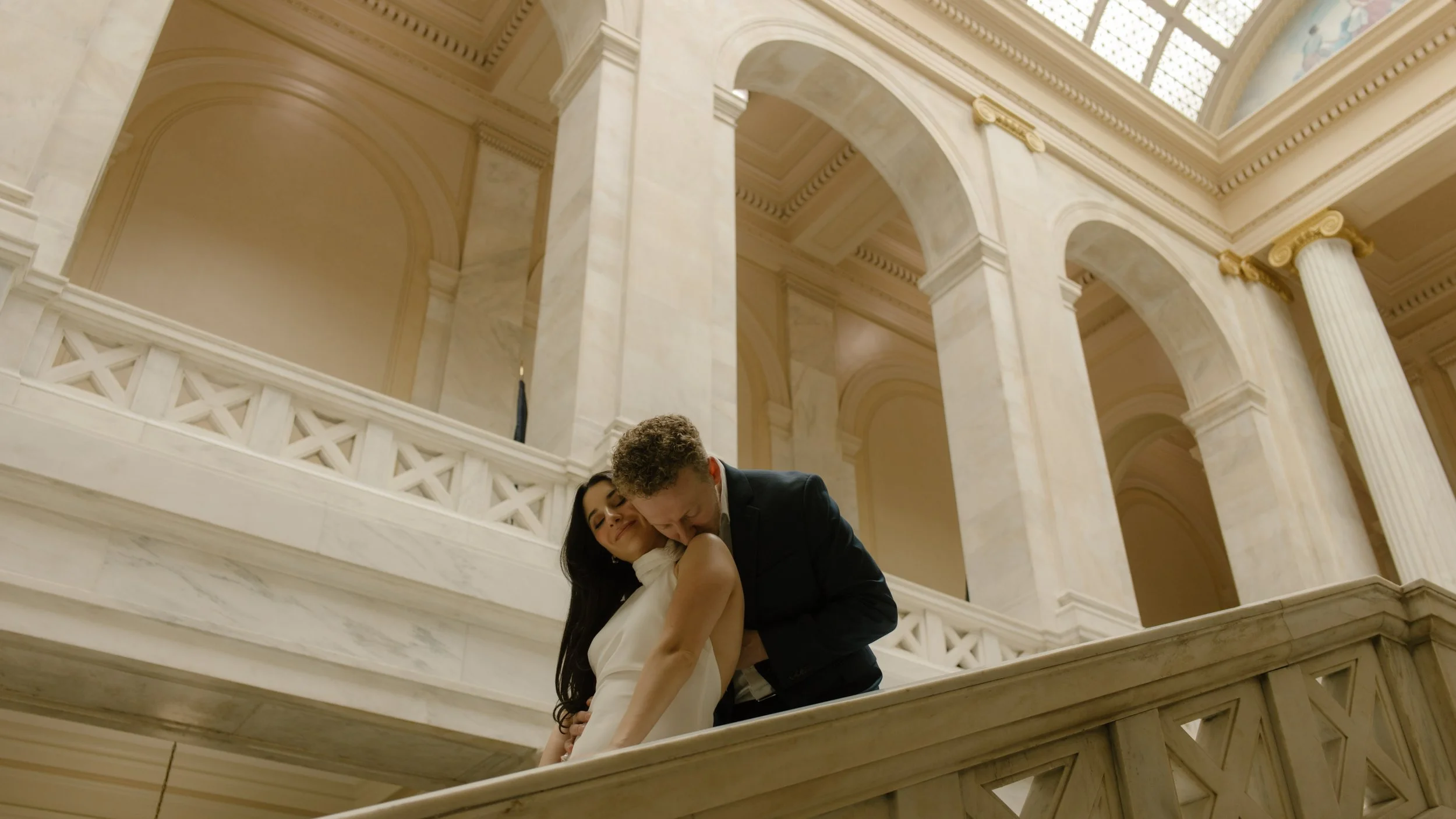 Groom embracing his bride on the staircase during a romantic Little Rock Courthouse engagement session
