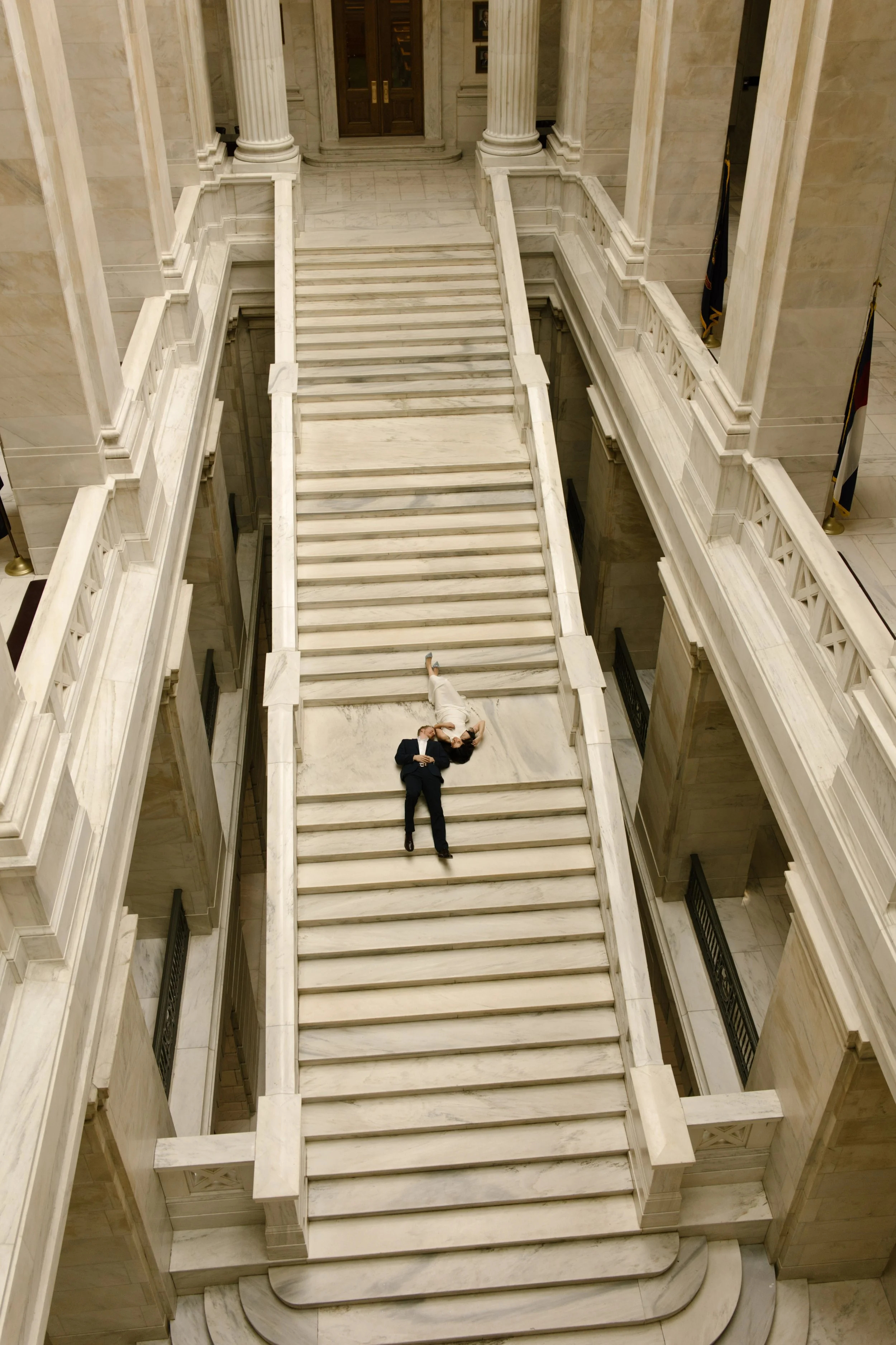 Overhead view of a couple lying together on the grand marble stairs of the courthouse