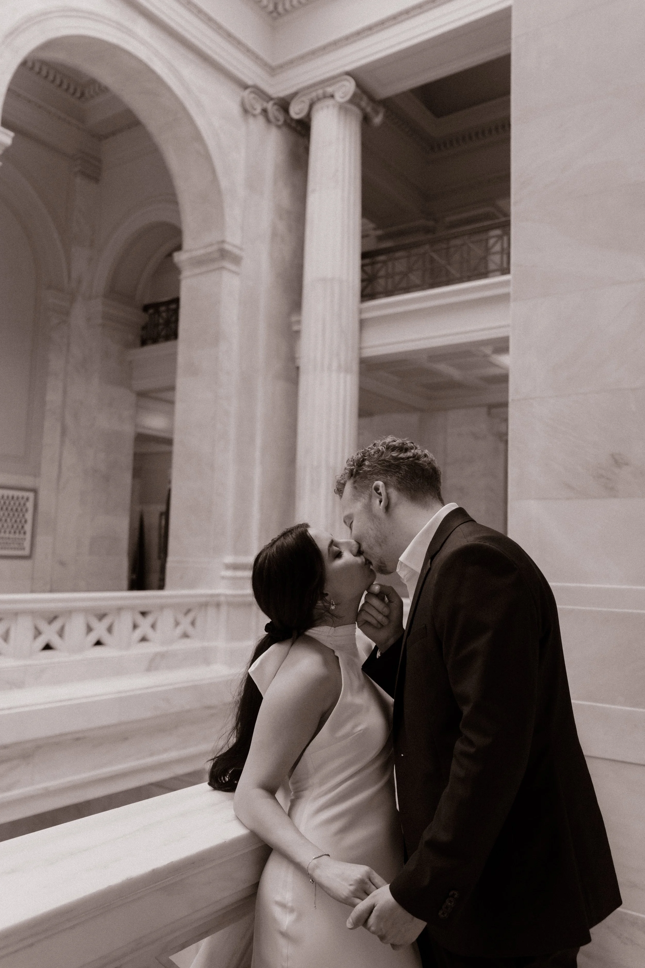 Black and white portrait of an engaged couple sharing a kiss inside the historic Little Rock Courthouse