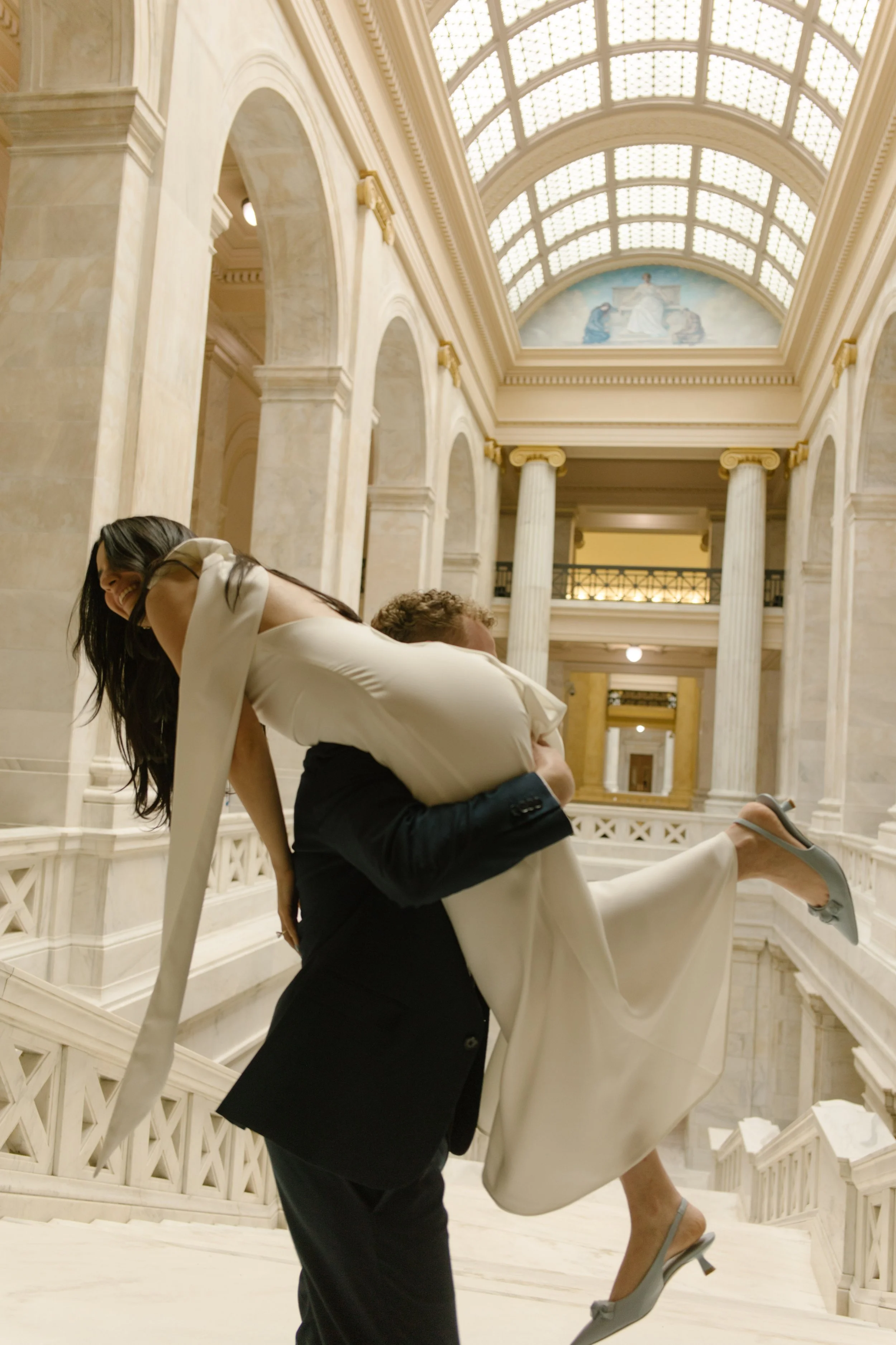 Groom lifting his bride on the staircase during a playful Little Rock Courthouse engagement session