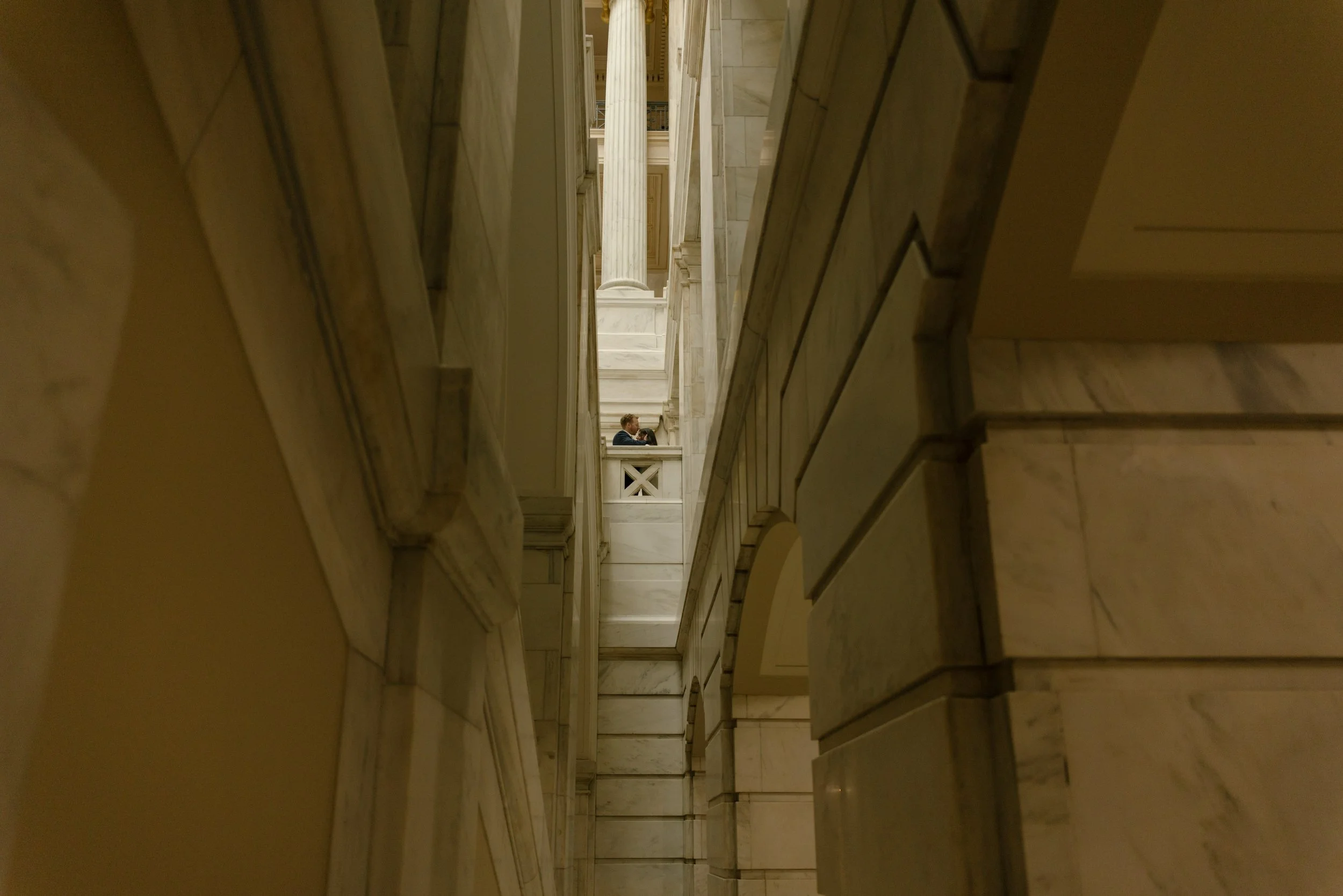 Intimate portrait framed by the marble corridors of the Little Rock courthouse, capturing a couple embracing on an upper balcony.