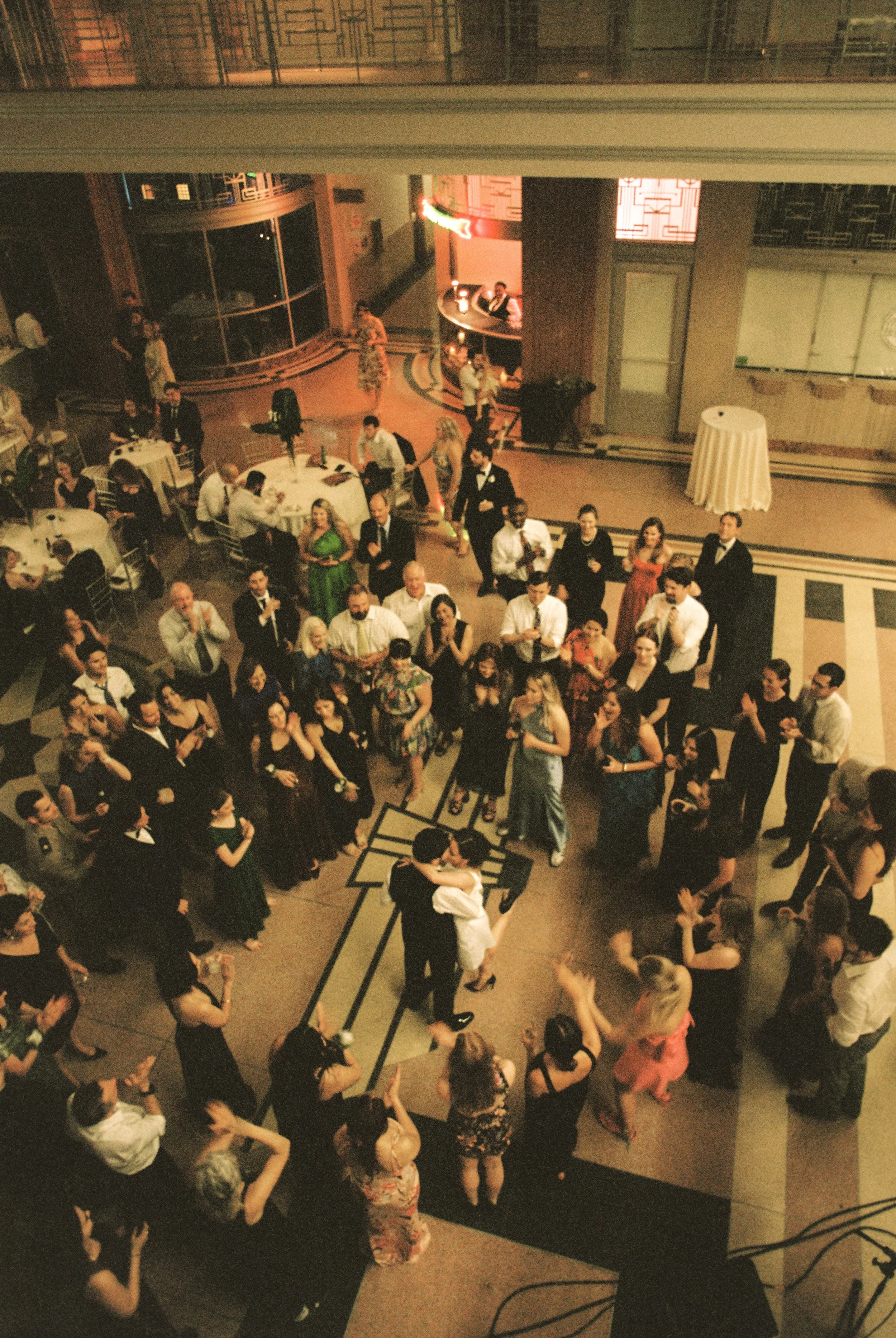 Overhead view of guests surrounding the newlyweds on the dance floor during a lively wedding reception.