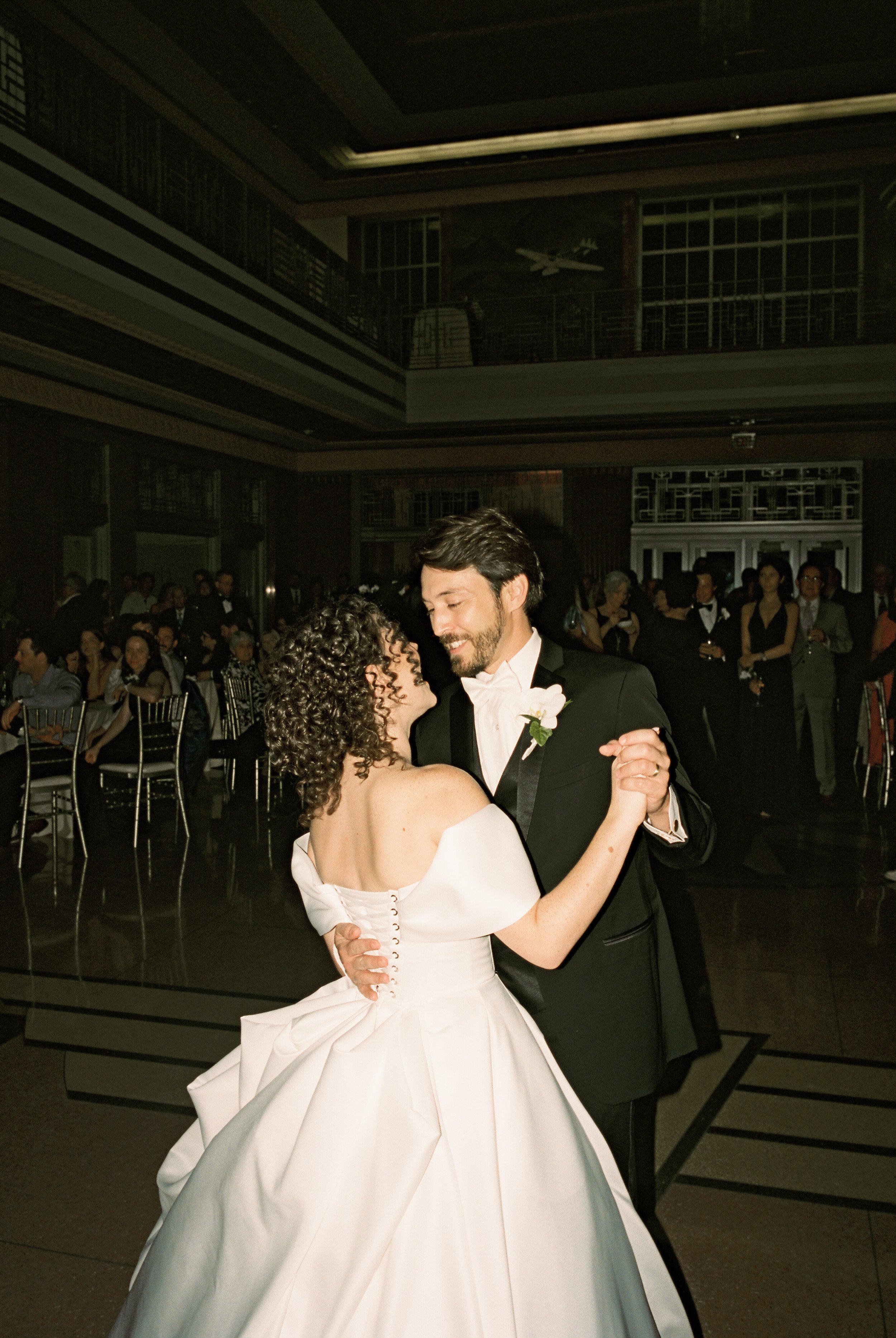 Bride and groom share their first dance beneath soft reception lighting in a timeless documentary wedding photography moment.