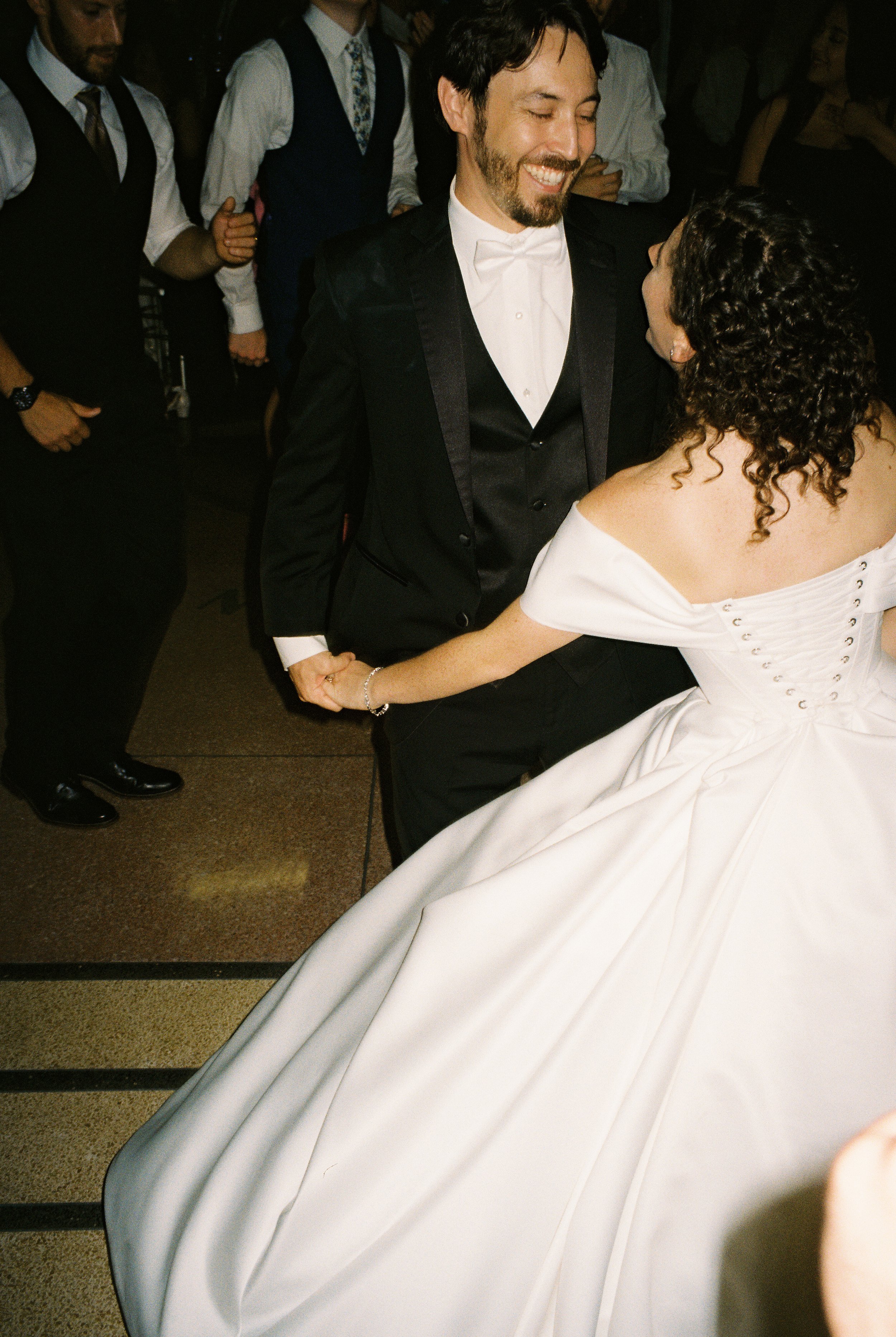Newlyweds dance together among guests during the reception, captured through authentic documentary wedding photography.