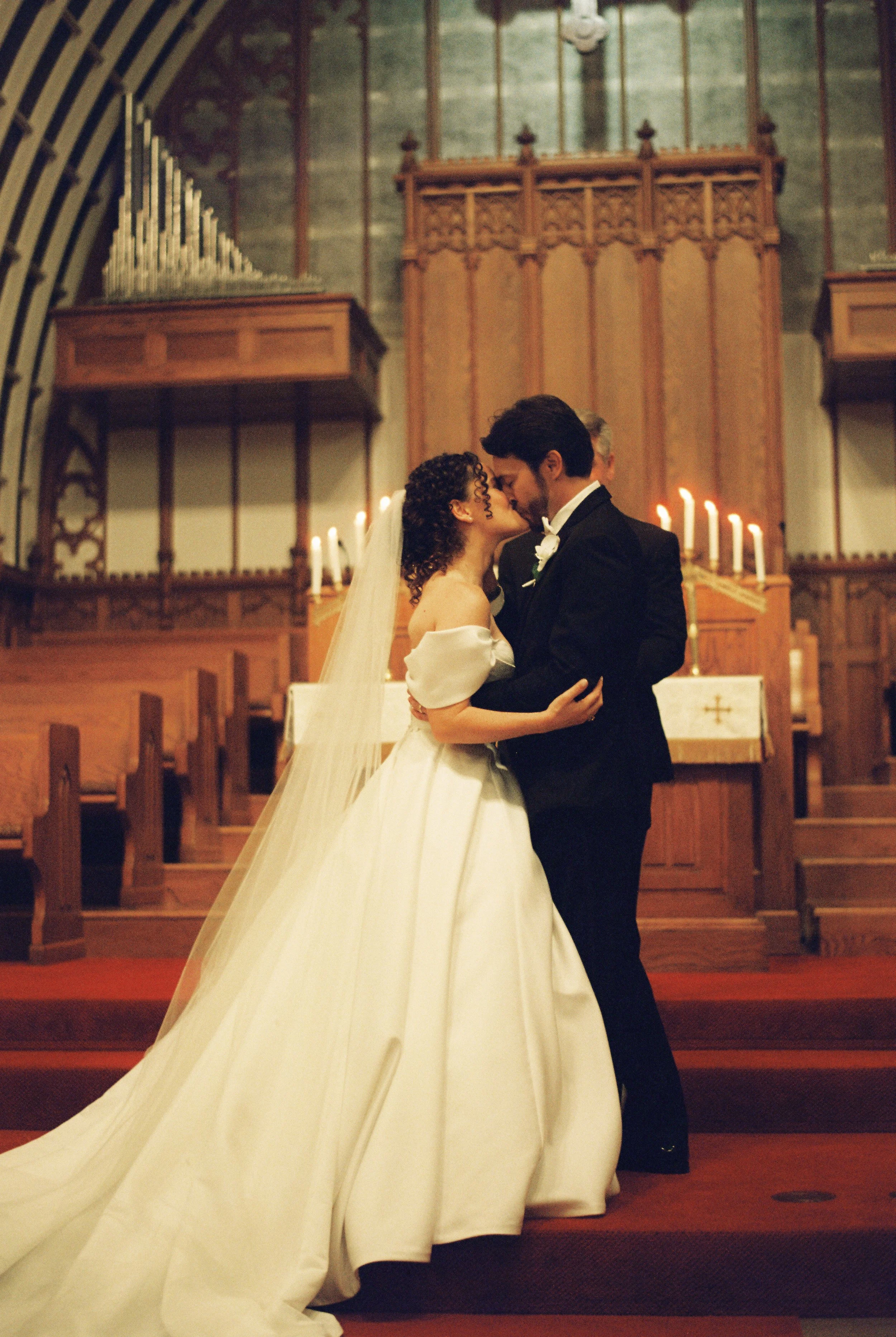 Bride and groom embrace in front of the church altar following their wedding ceremony in a classic portrait.