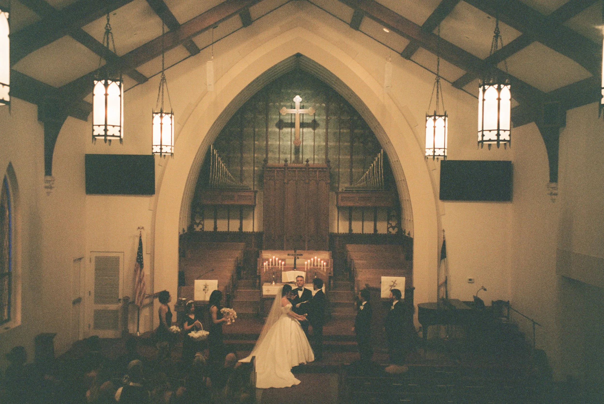 Newlyweds share their first kiss in the church aisle as guests applaud in a joyful documentary wedding photography scene.