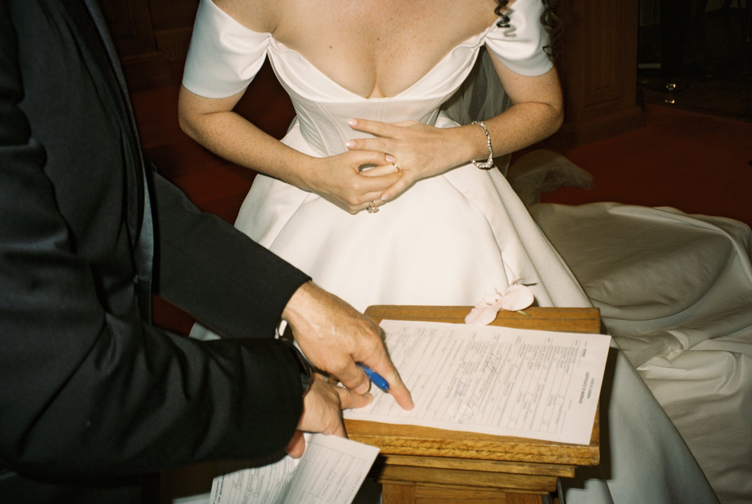 Close-up of the marriage license signing process during the wedding ceremony in a documentary wedding photography style.