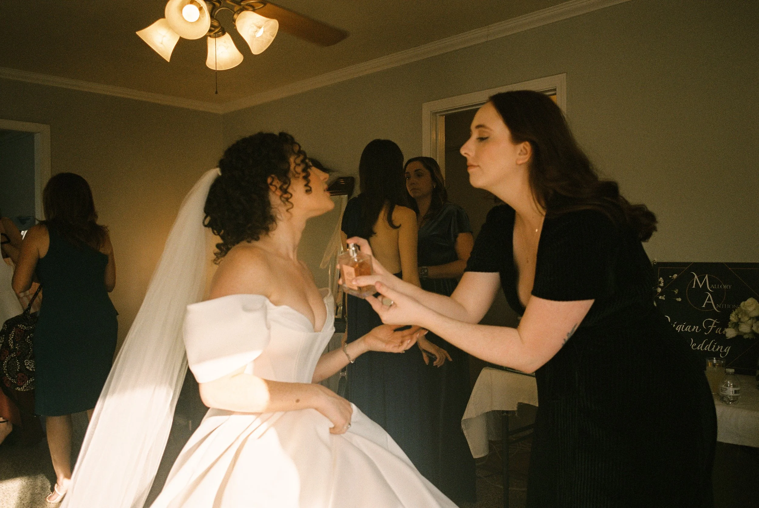 Bridesmaid helps the bride with a final touch while getting ready before the ceremony.