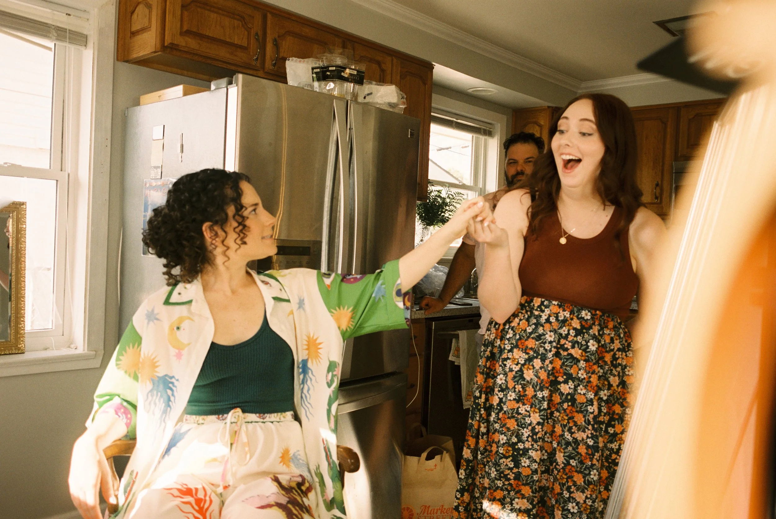 Bride shares a joyful hand squeeze with a friend during wedding morning preparations.