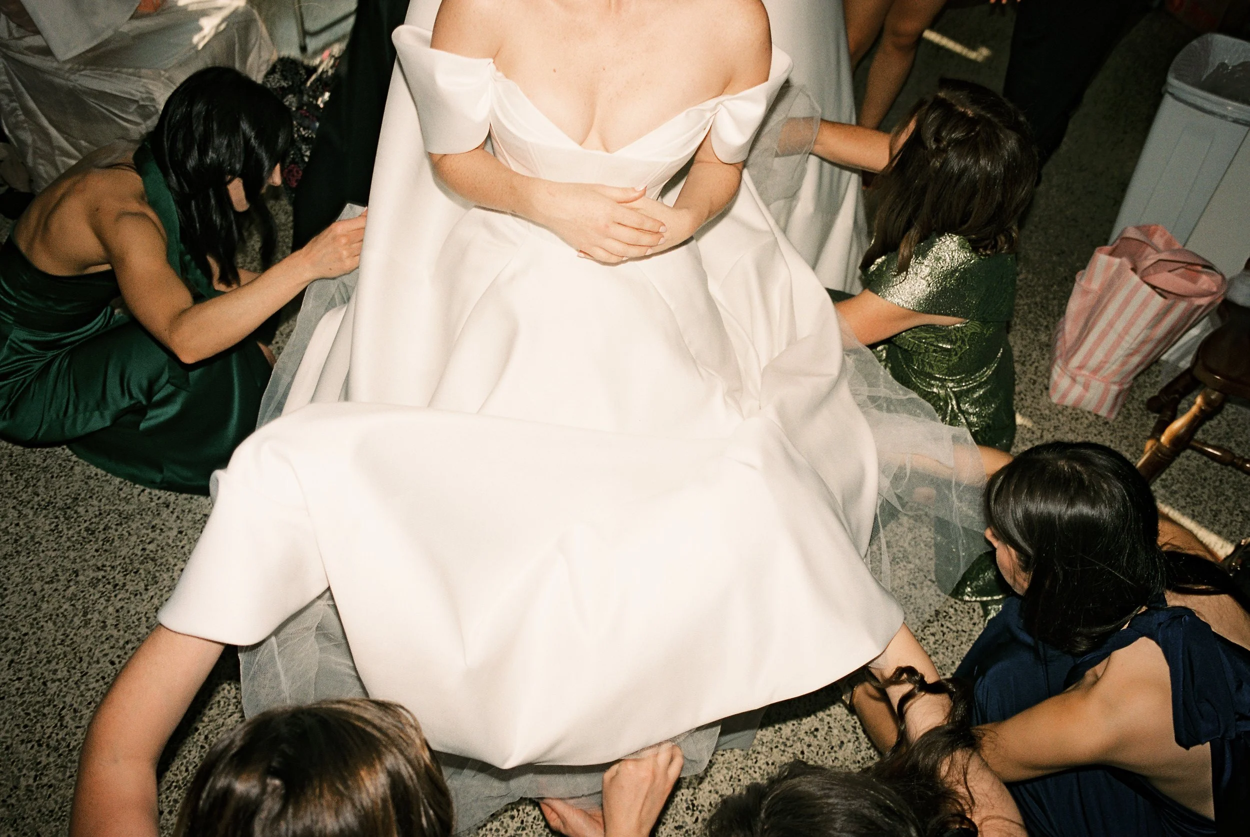 Bridesmaids gather around the bride to arrange her wedding gown before the ceremony.