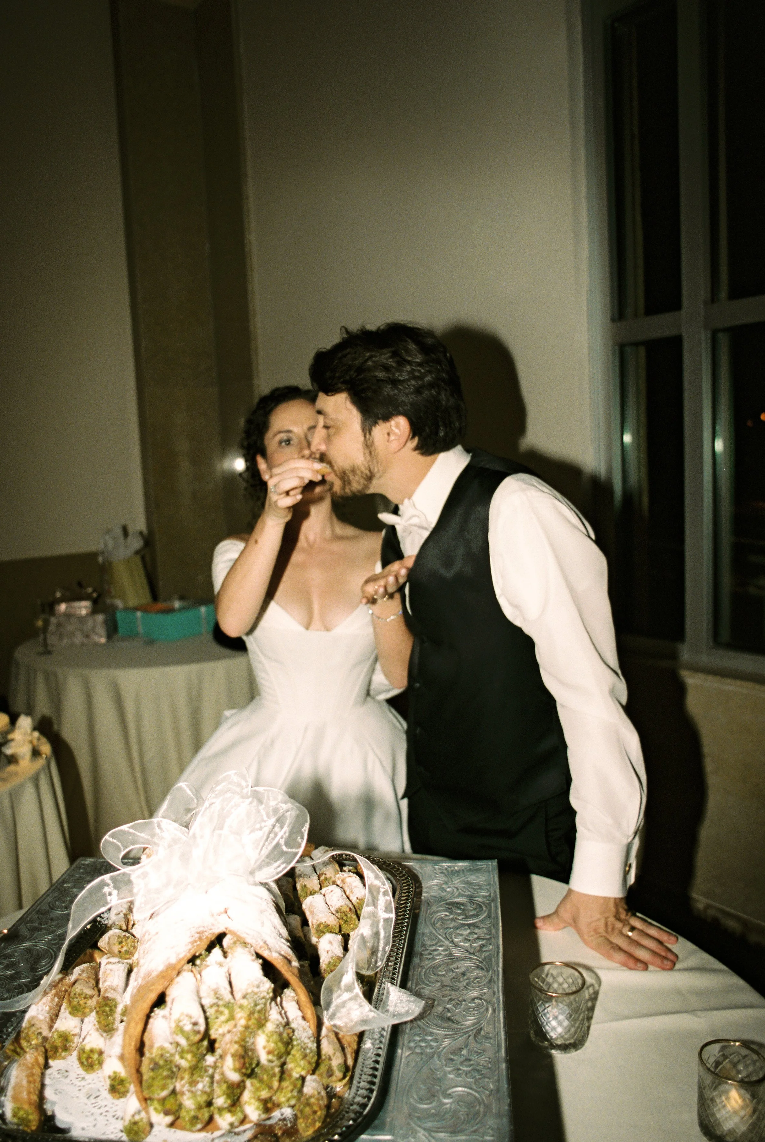 Bride feeds the groom a bite of dessert during the reception in a playful wedding moment.