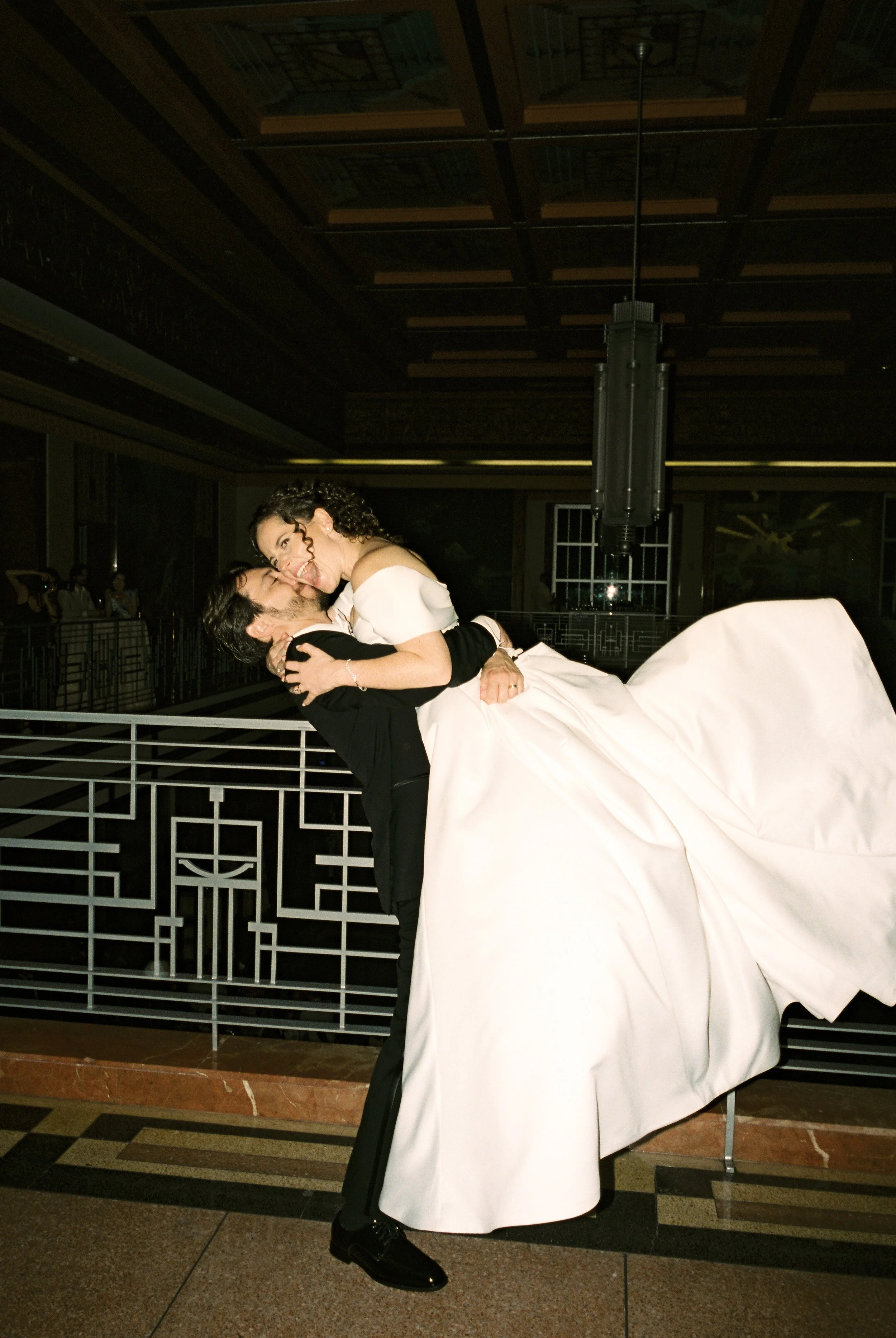 Groom lifts the bride during a romantic dance at the reception, showcasing the movement of her gown.