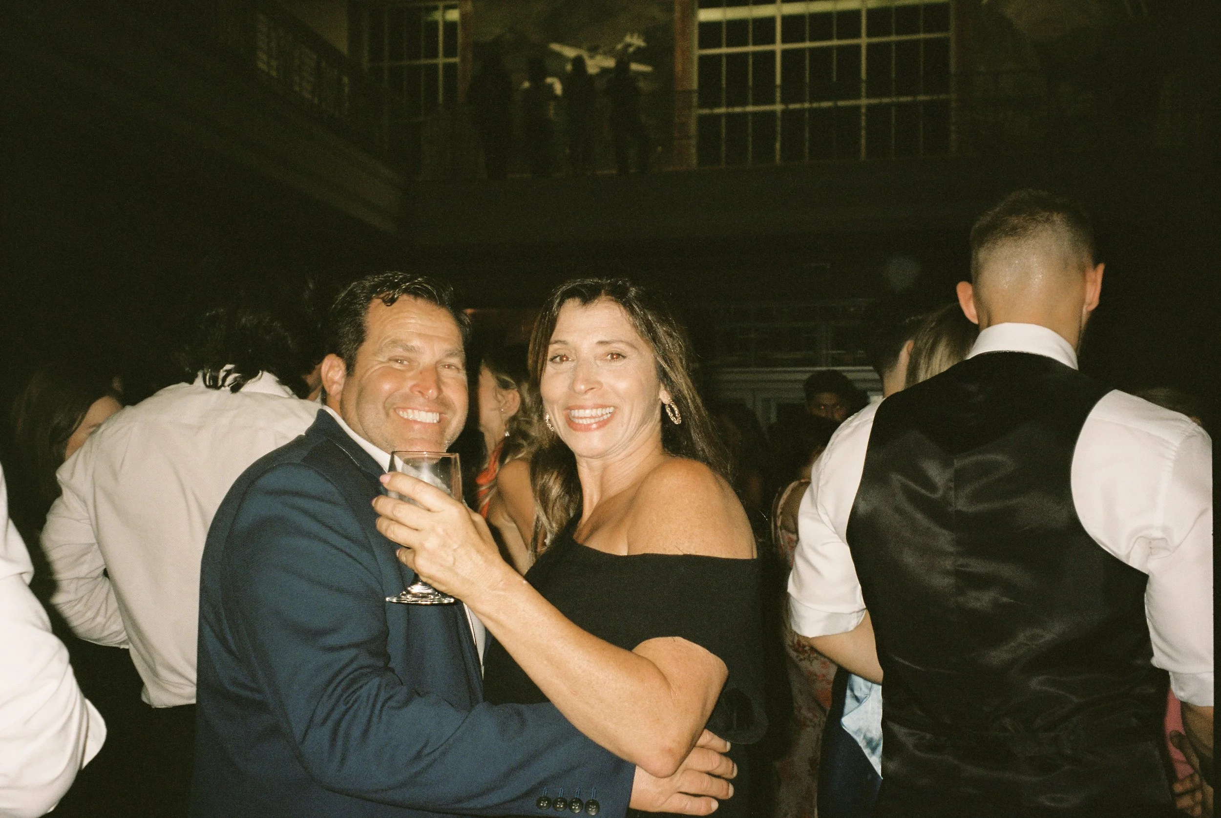 Wedding guests smile and dance together during the reception, enjoying the evening celebration.
