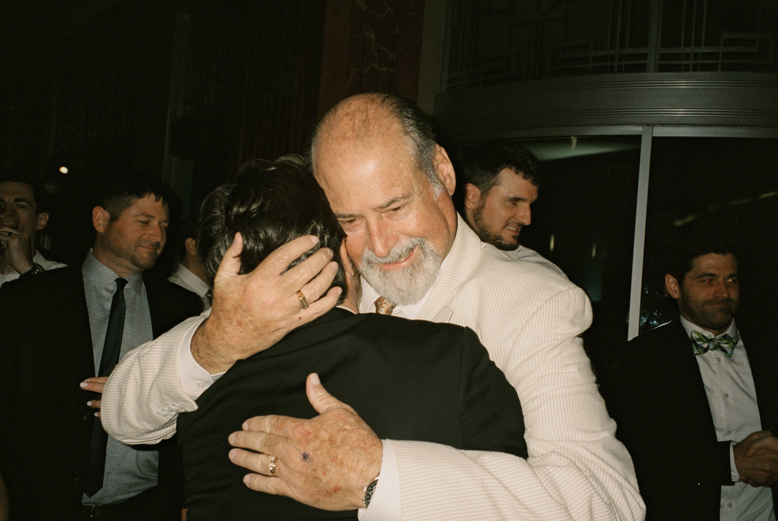 Emotional embrace between the groom and an older family member during the wedding reception.