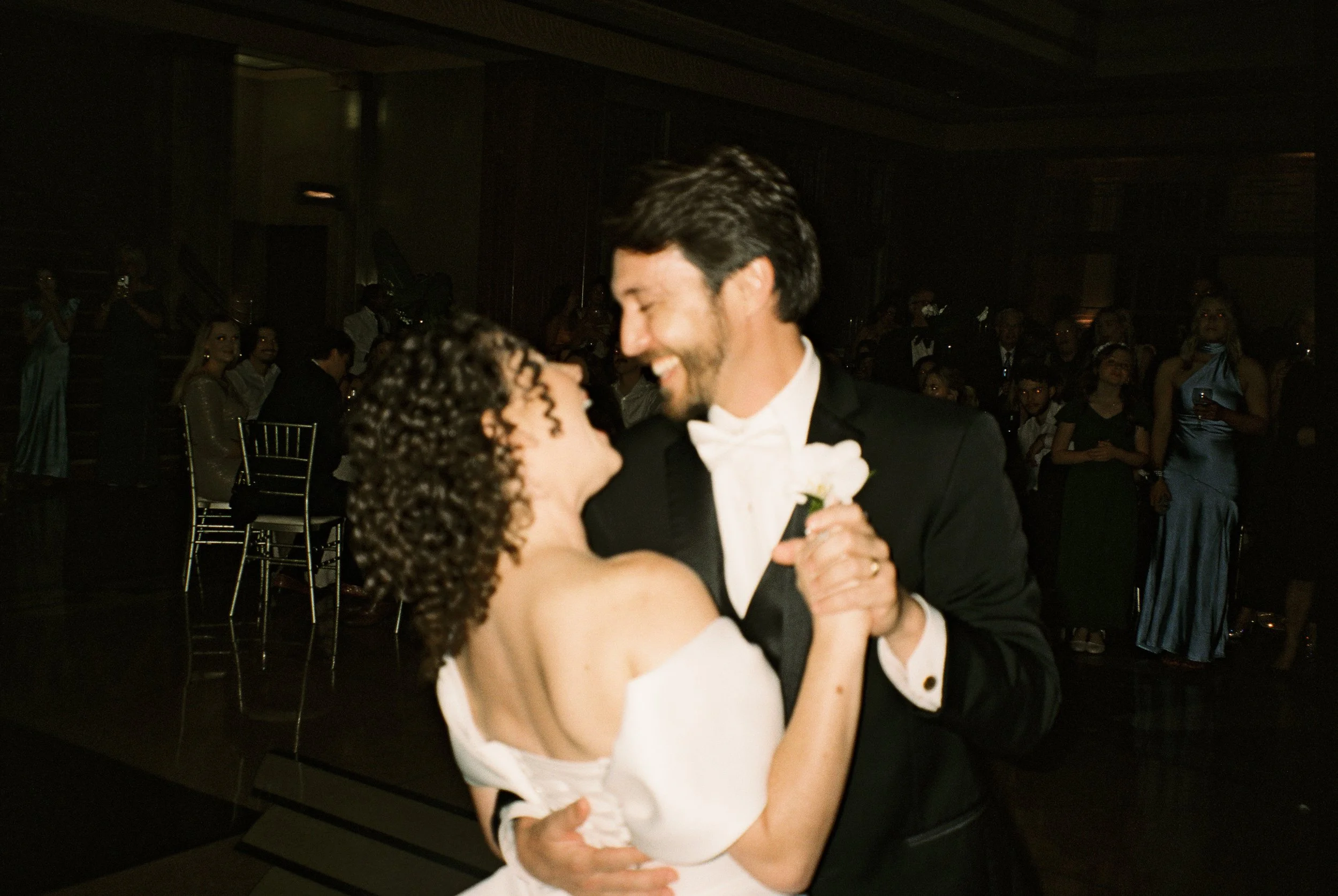 Newlyweds sharing a dance on the reception floor, smiling and laughing together.