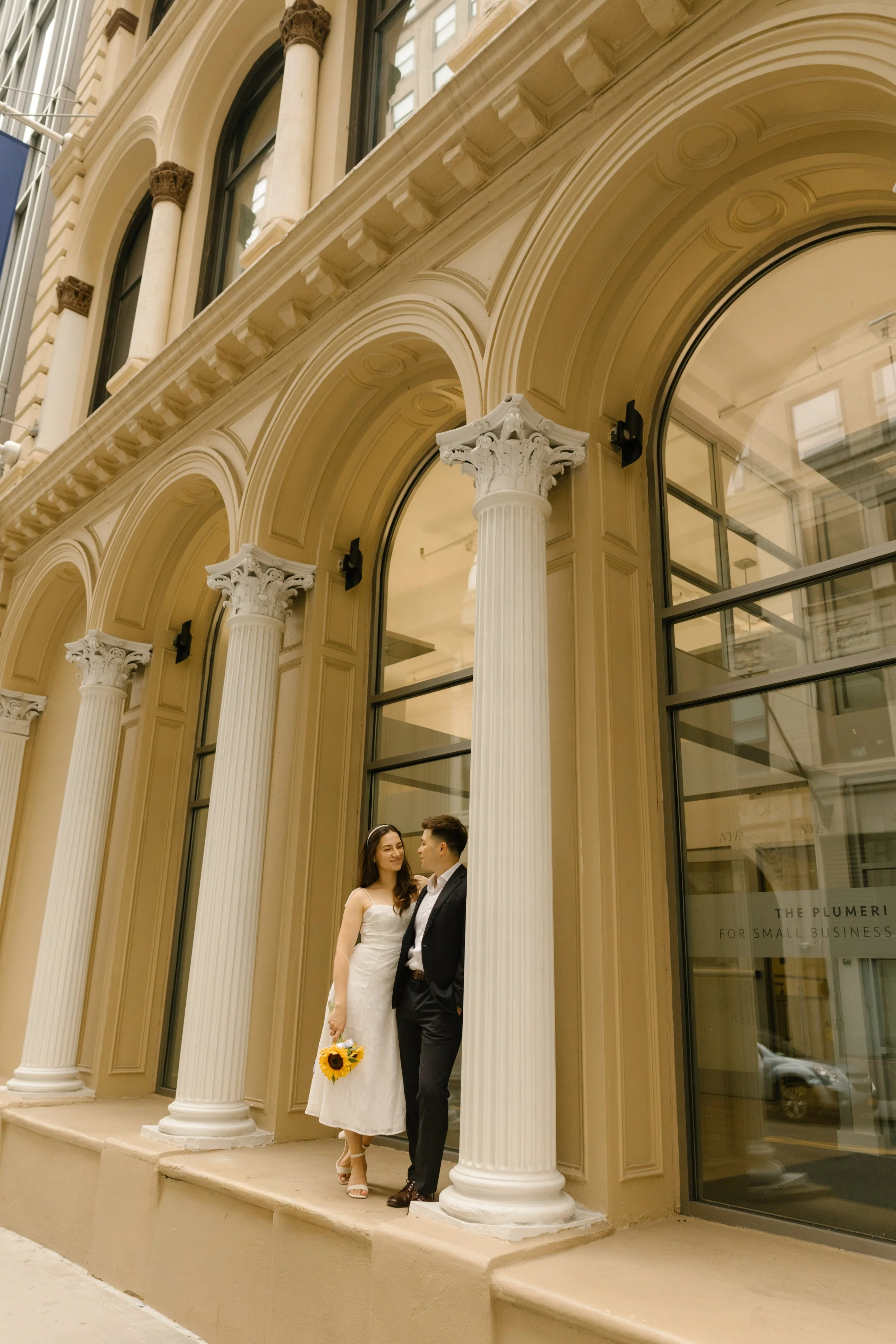 Bride and groom standing beneath elegant columns in SoHo, showcasing timeless architecture and Wedding Locations in NYC for wedding portraits.
