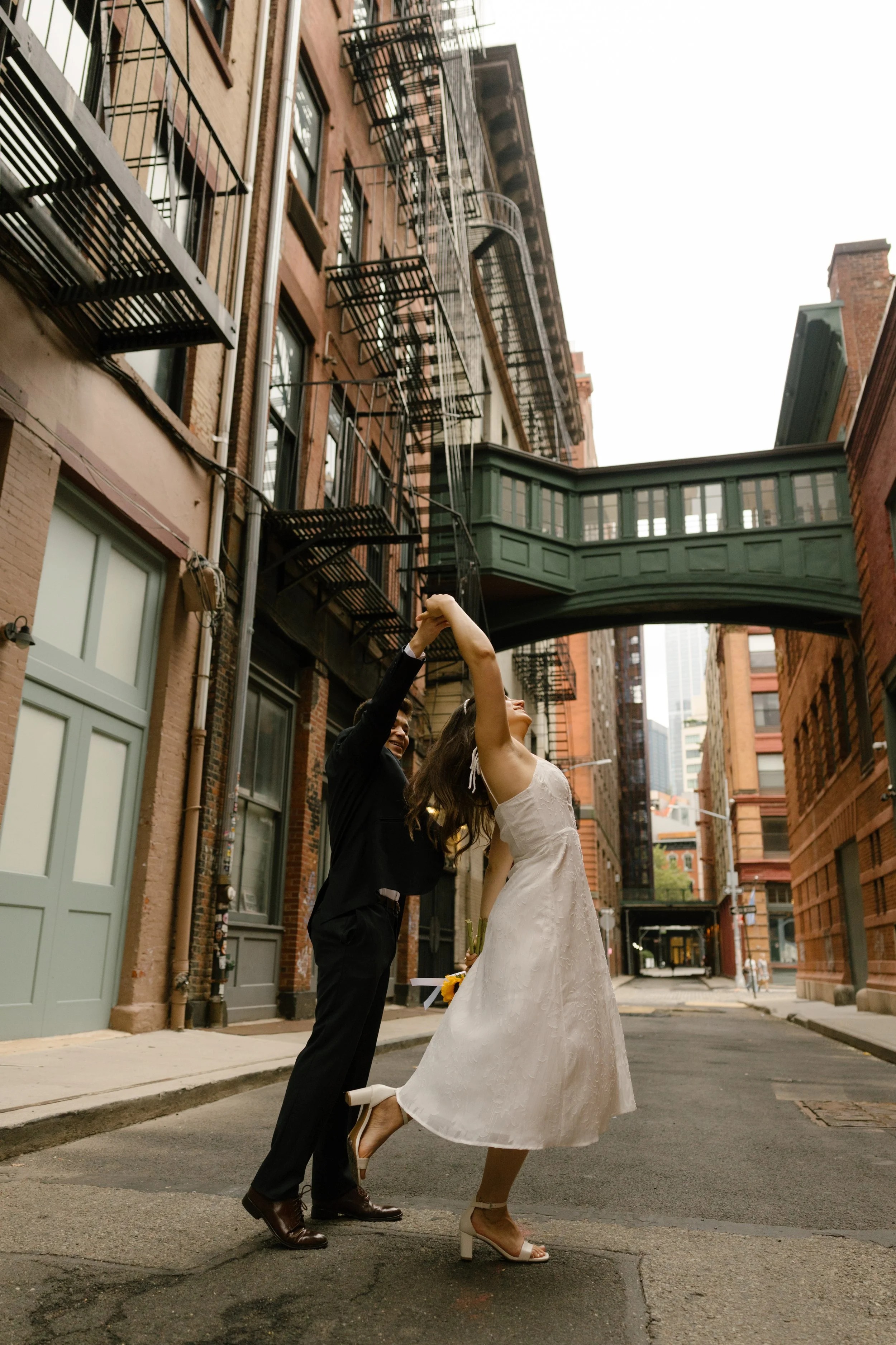 Bride and groom twirl together beneath the iconic skybridge in DUMBO, one of the most recognizable Wedding Locations in NYC.