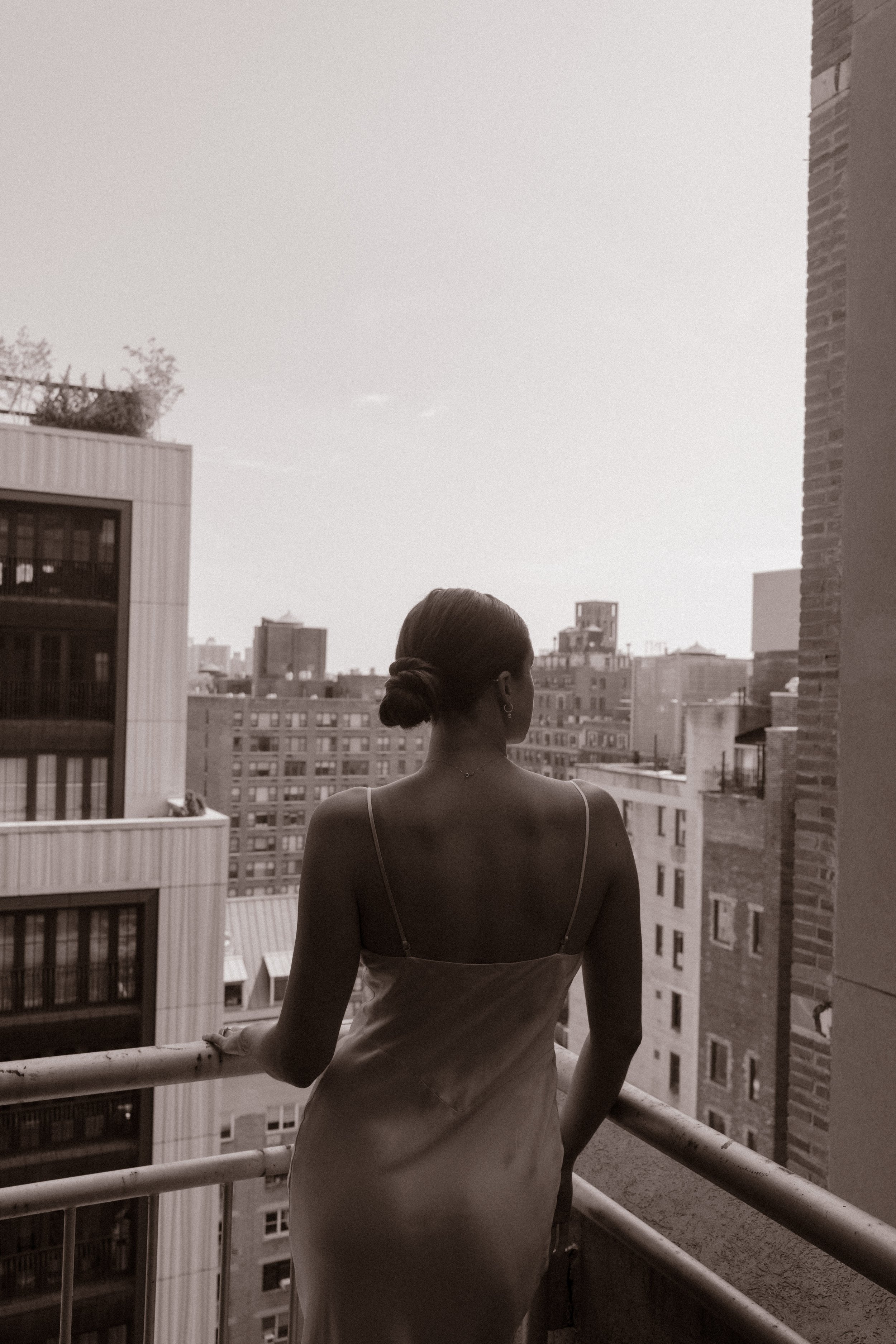 Bride overlooks the Manhattan skyline from a hotel balcony before her wedding, showcasing elegant Wedding Locations in NYC.