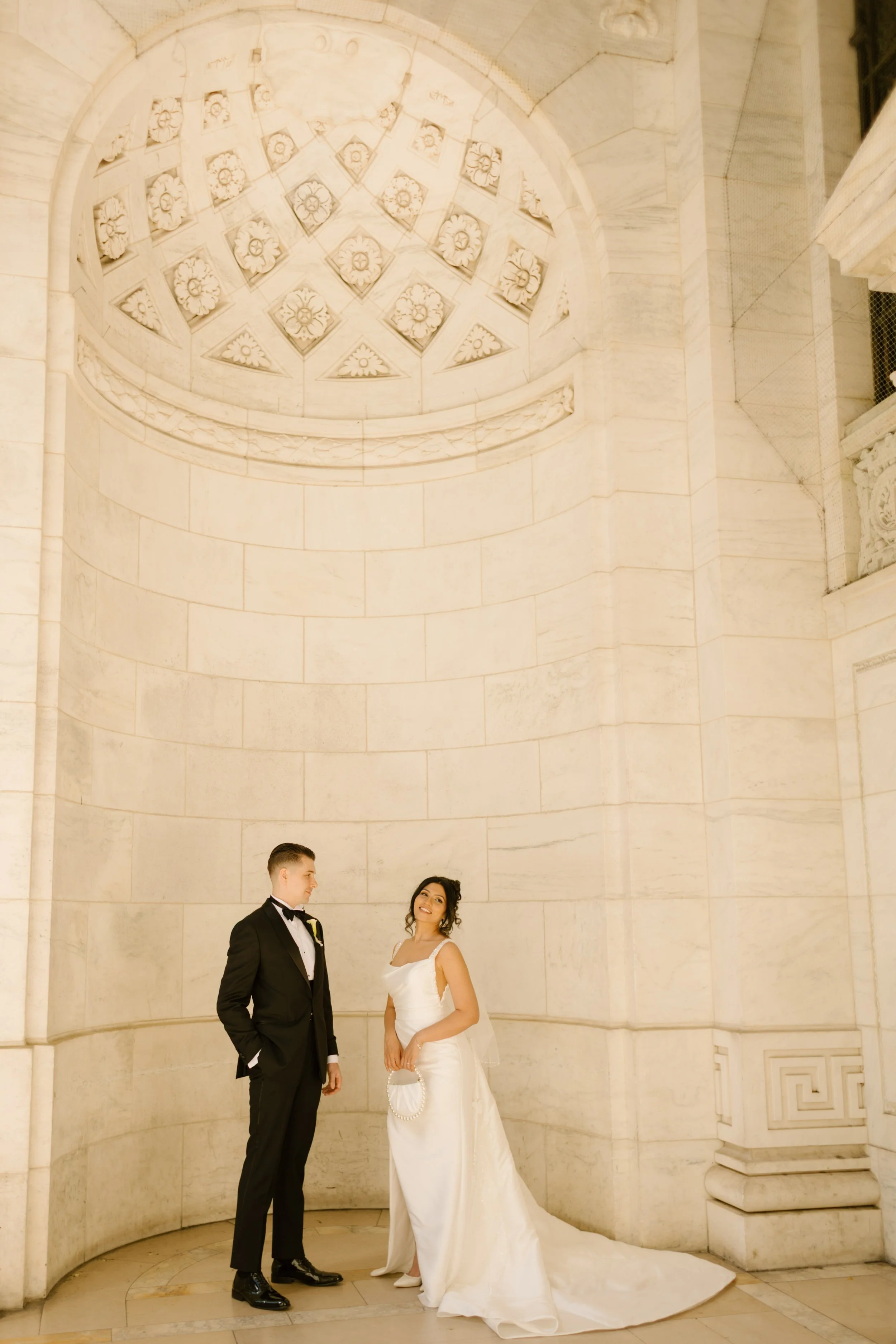 Elegant bride and groom posing beneath grand marble architecture at a classic Wedding Locations in NYC portrait location.