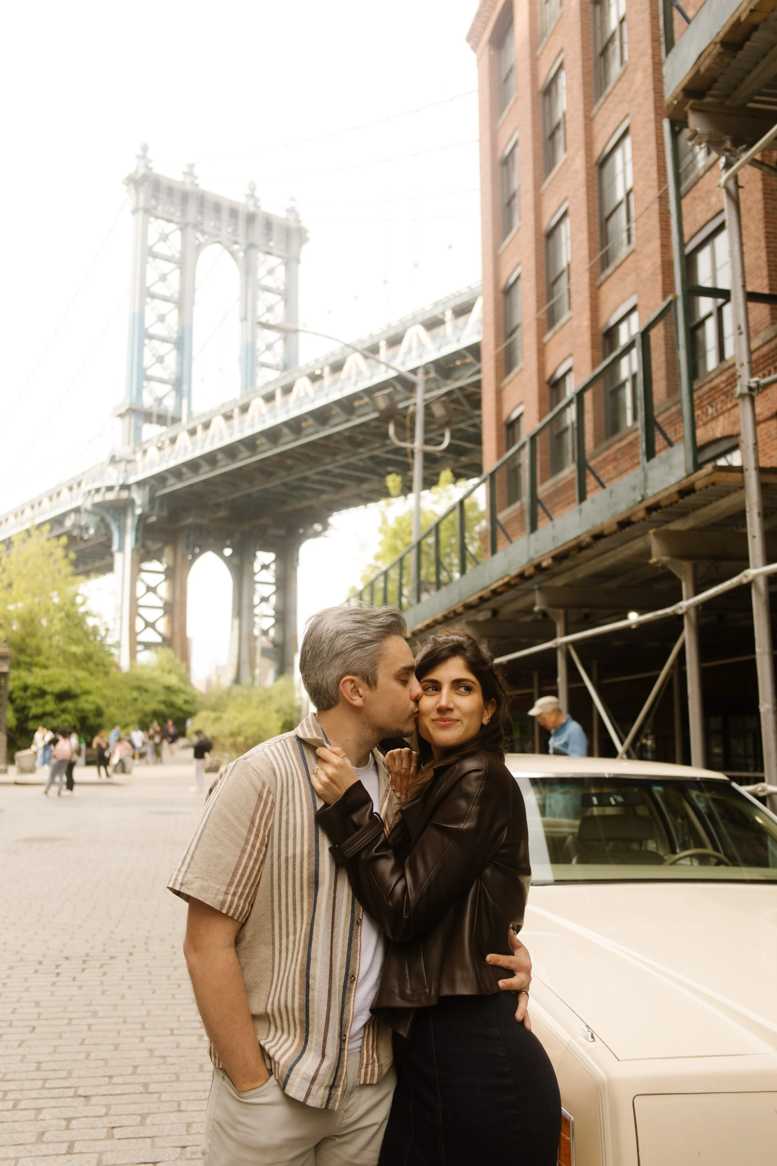Couple embraces beneath the Manhattan Bridge in DUMBO, one of the most photographed Wedding Locations in NYC.