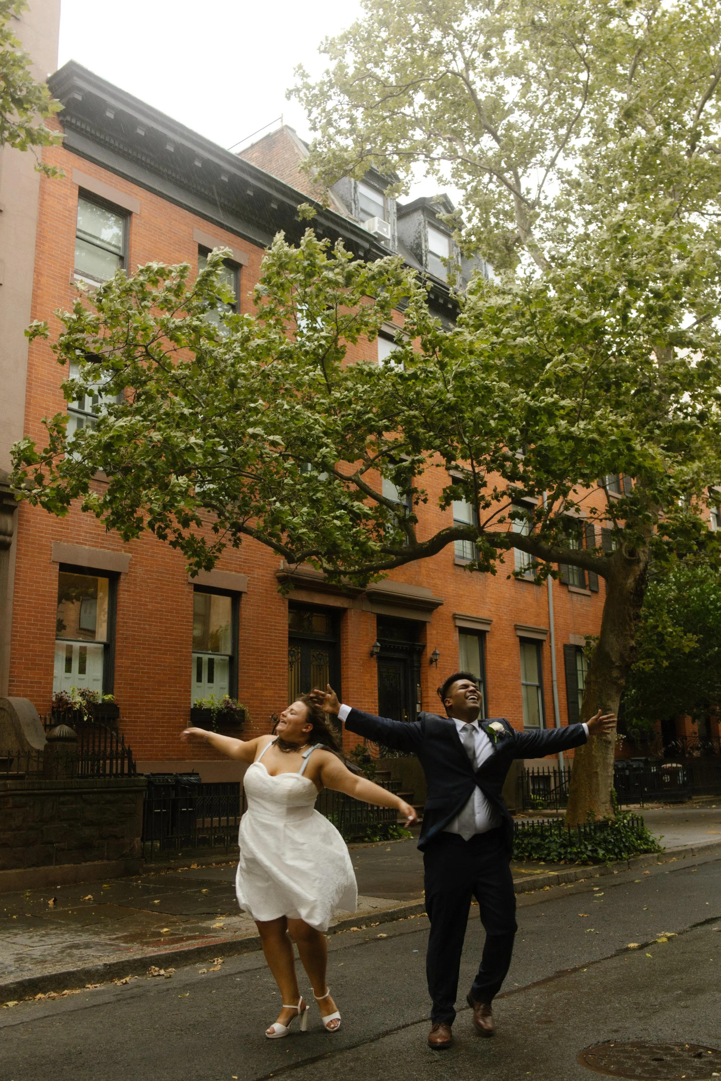 Newlyweds celebrate together on a tree-lined Brooklyn brownstone street after their intimate wedding.
