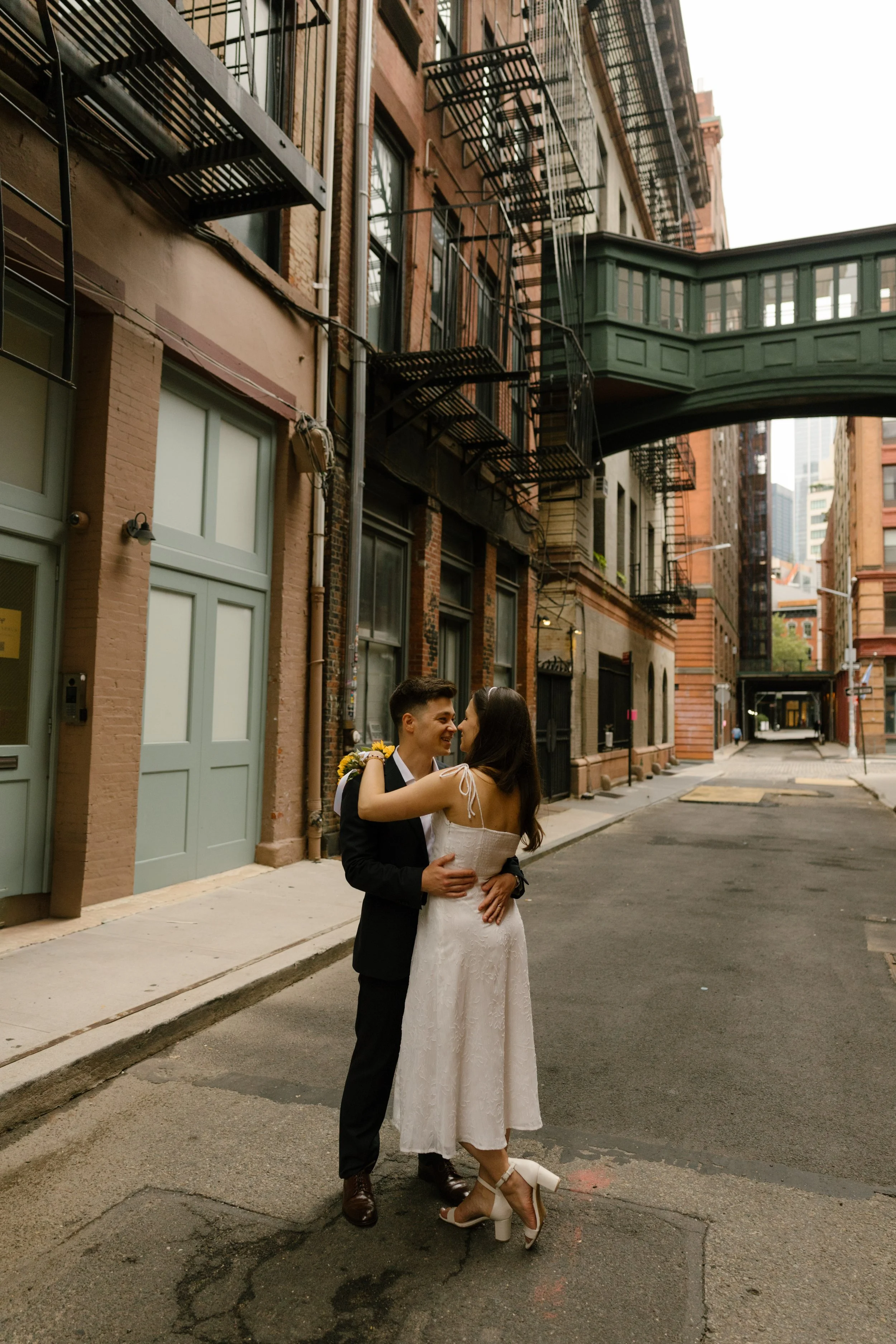 Bride and groom hug beneath the iconic DUMBO skybridge, capturing timeless Wedding Locations in NYC.