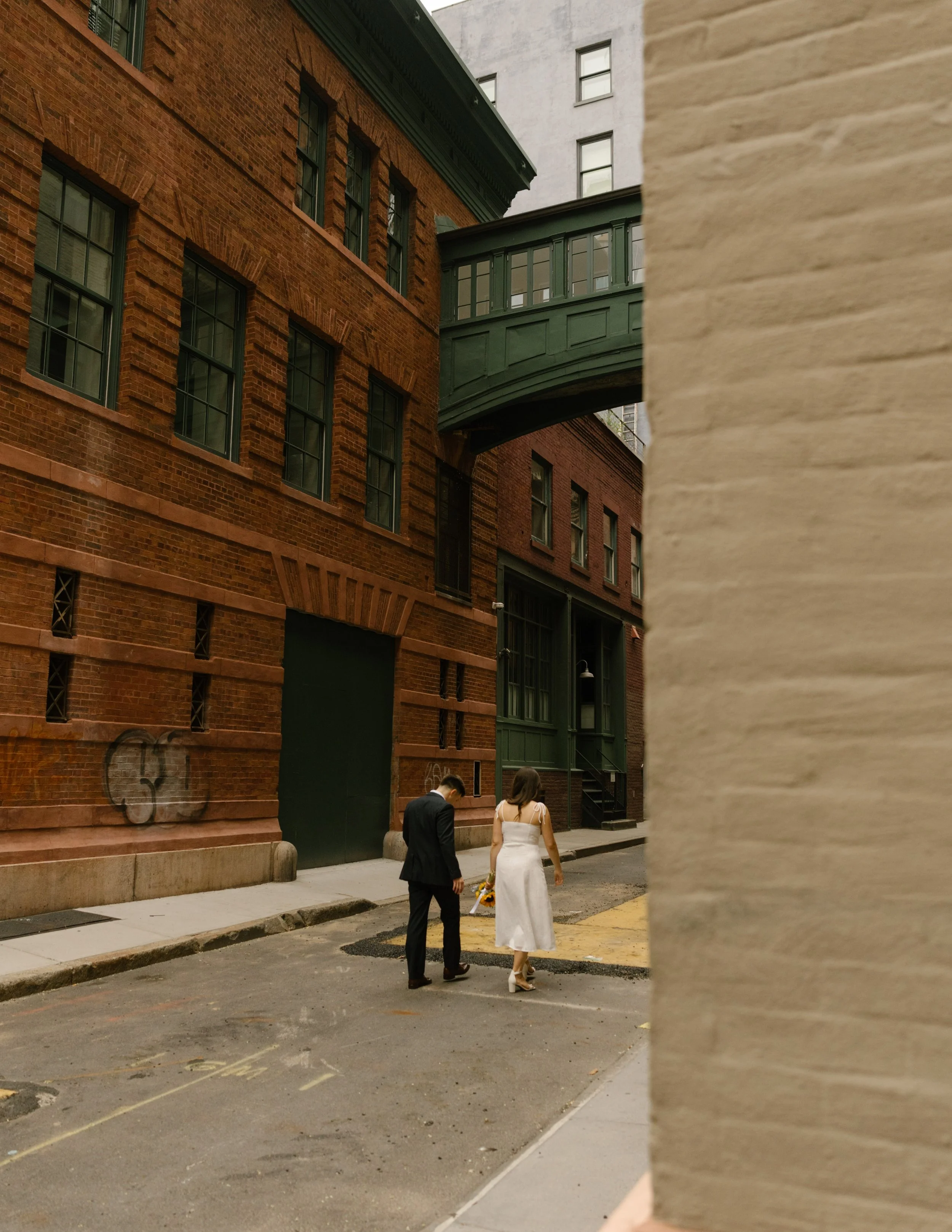 Bride and groom stroll beneath the DUMBO skybridge after their city wedding, showcasing iconic Wedding Locations in NYC.