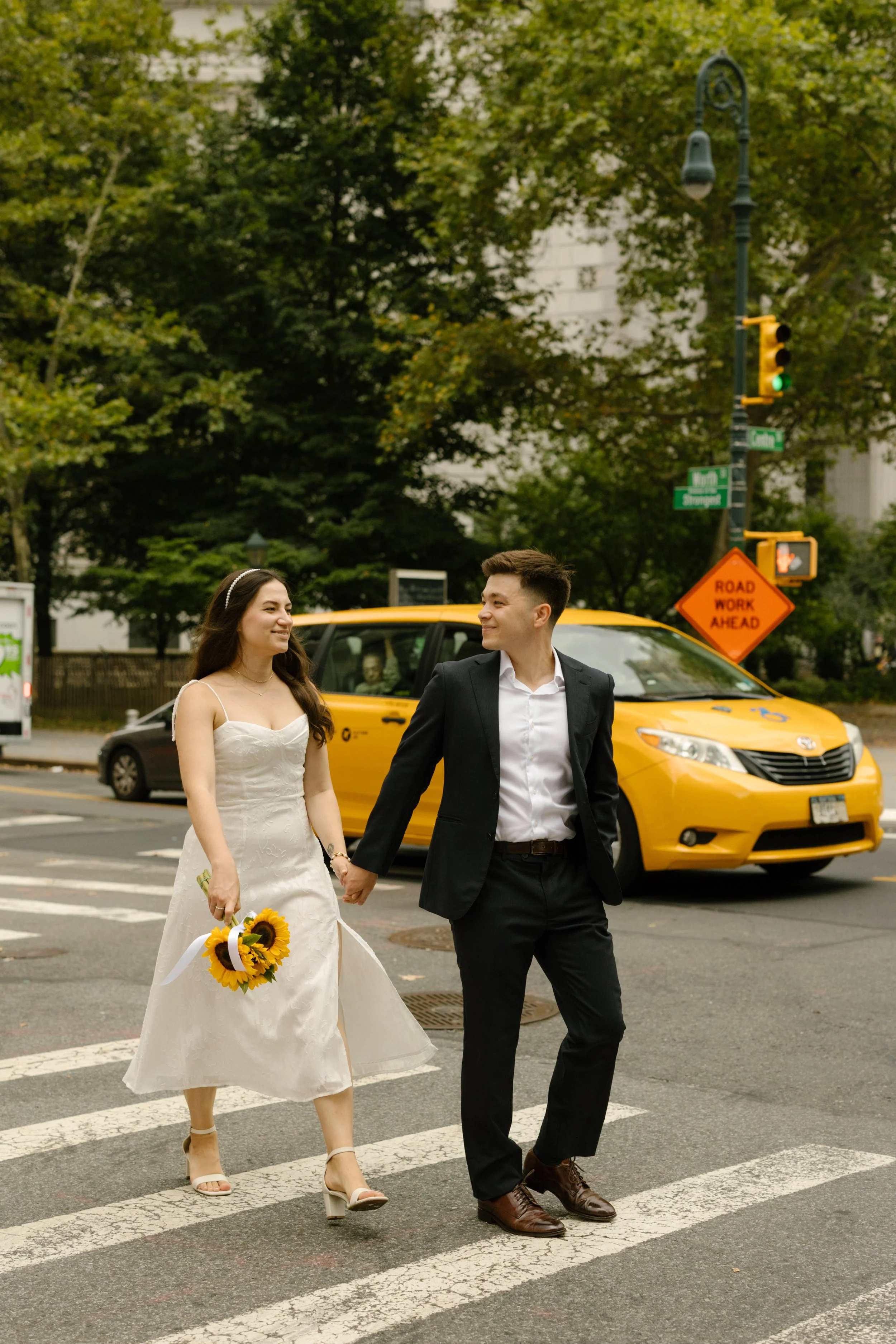 Bride and groom embrace beneath the iconic DUMBO skybridge with One World Trade Center in the background, showcasing Wedding Locations in NYC.