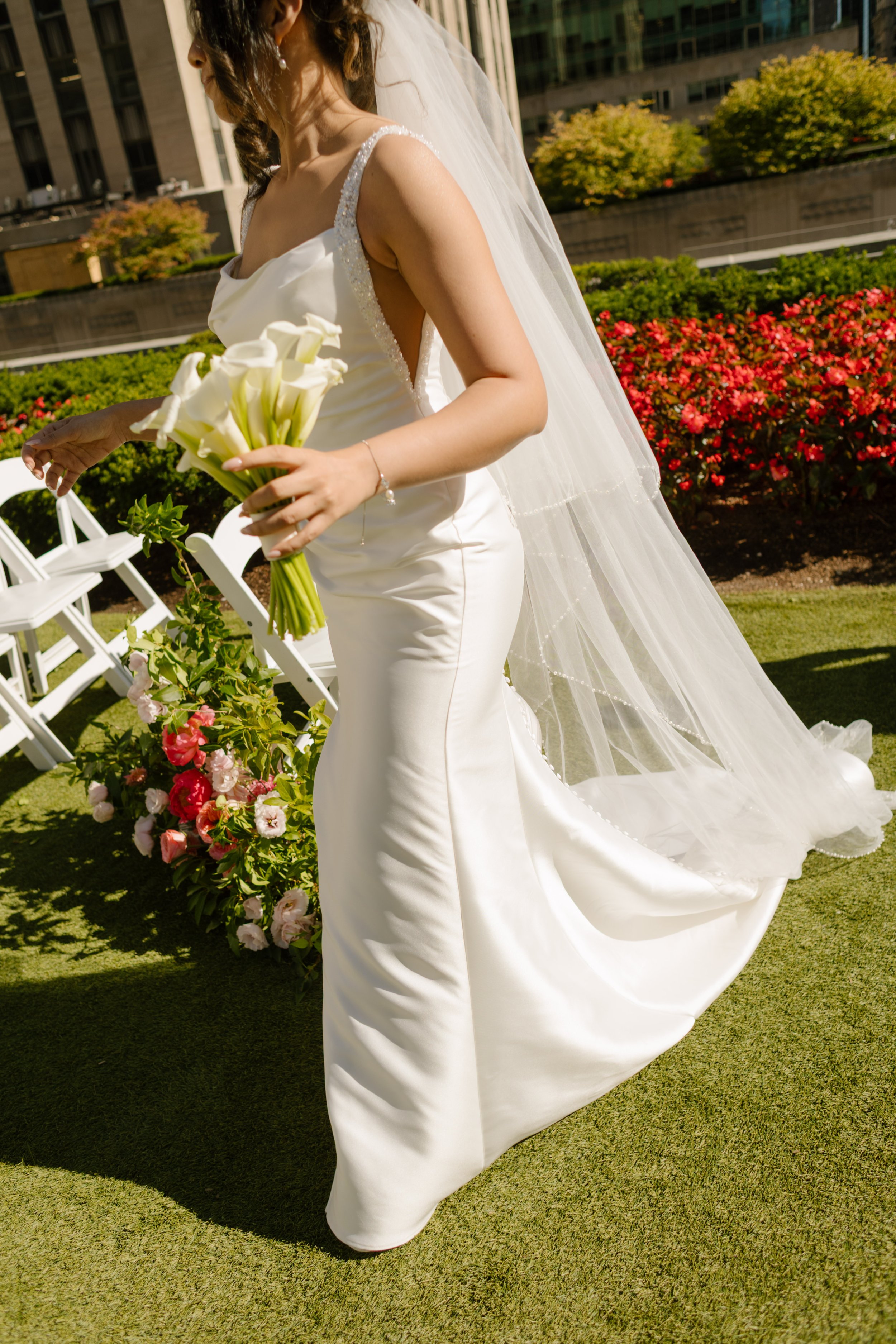 Bride walks through a rooftop ceremony space with calla lily bouquet, highlighting elegant Wedding Locations in NYC.