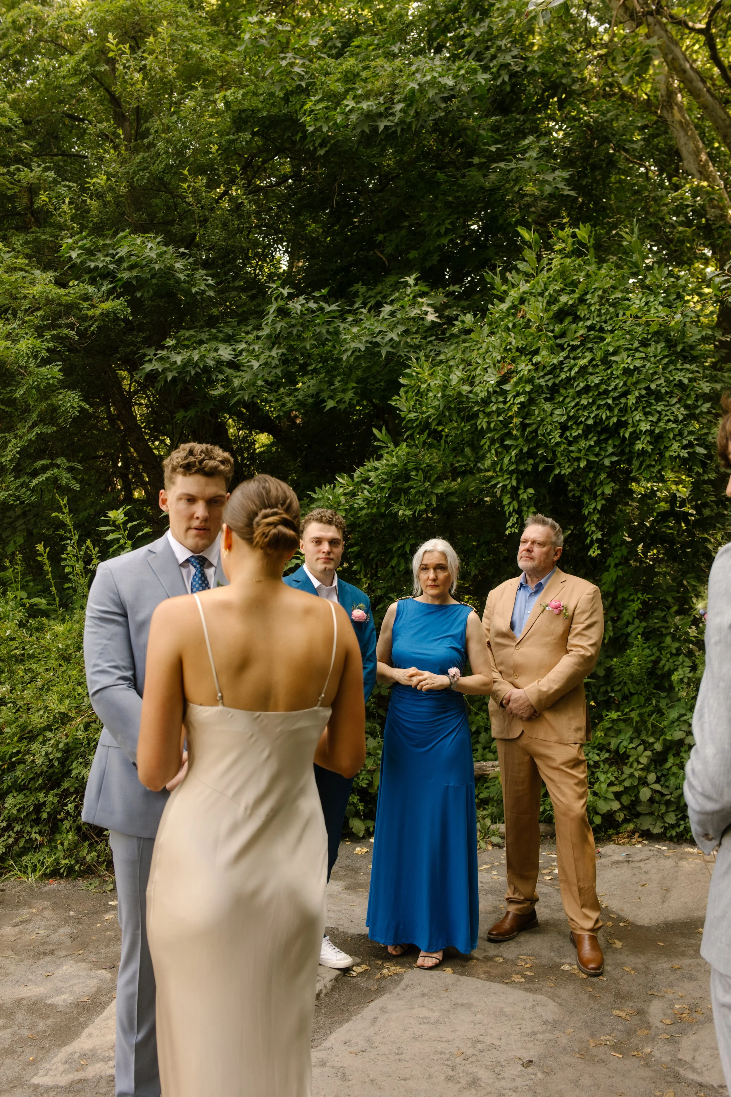 Couple exchanges vows during an intimate Central Park ceremony surrounded by family and lush greenery at one of the most romantic Wedding Locations in NYC.