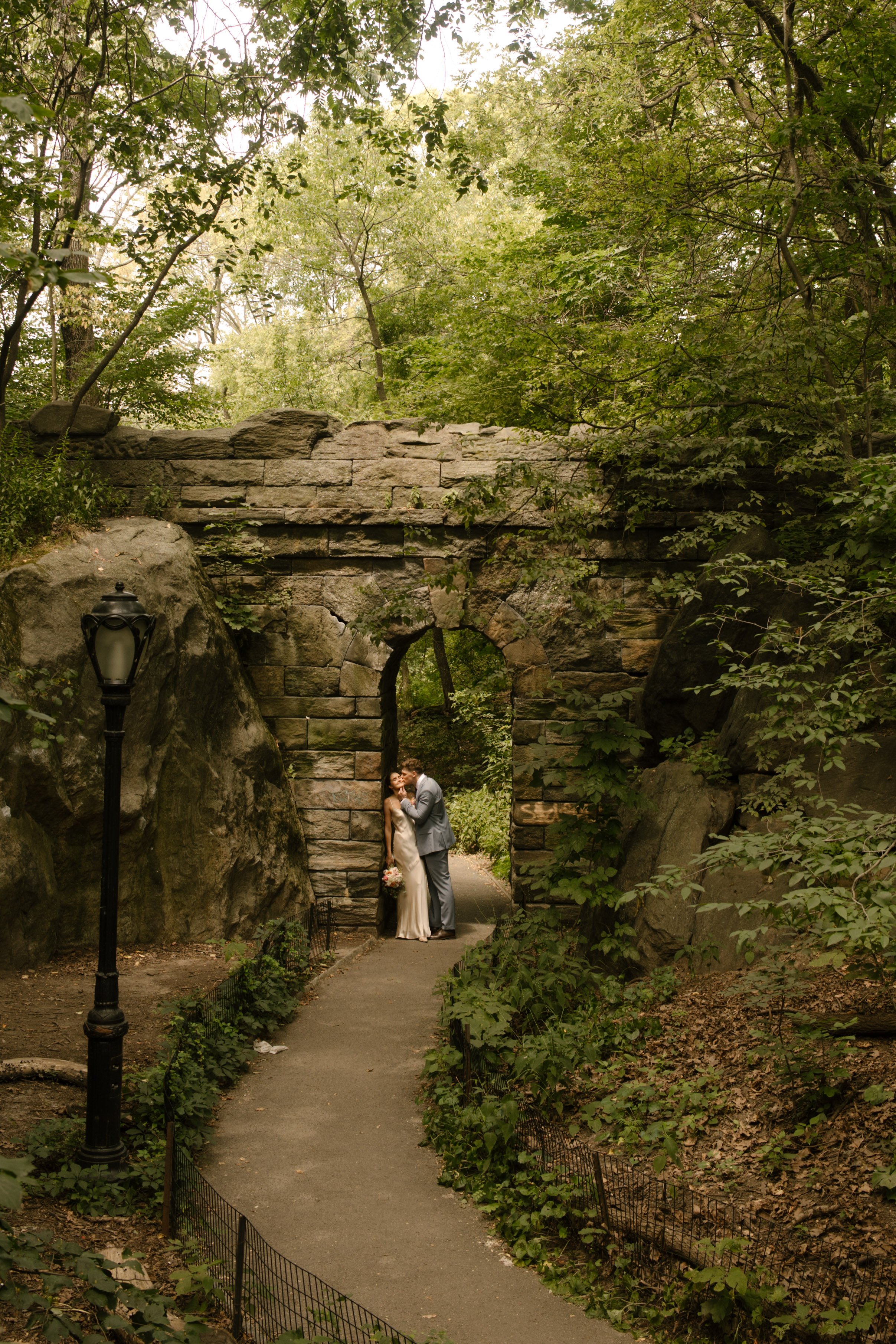 Couple embraces beneath the historic stone arch in Central Park, one of the most iconic Wedding Locations in NYC.