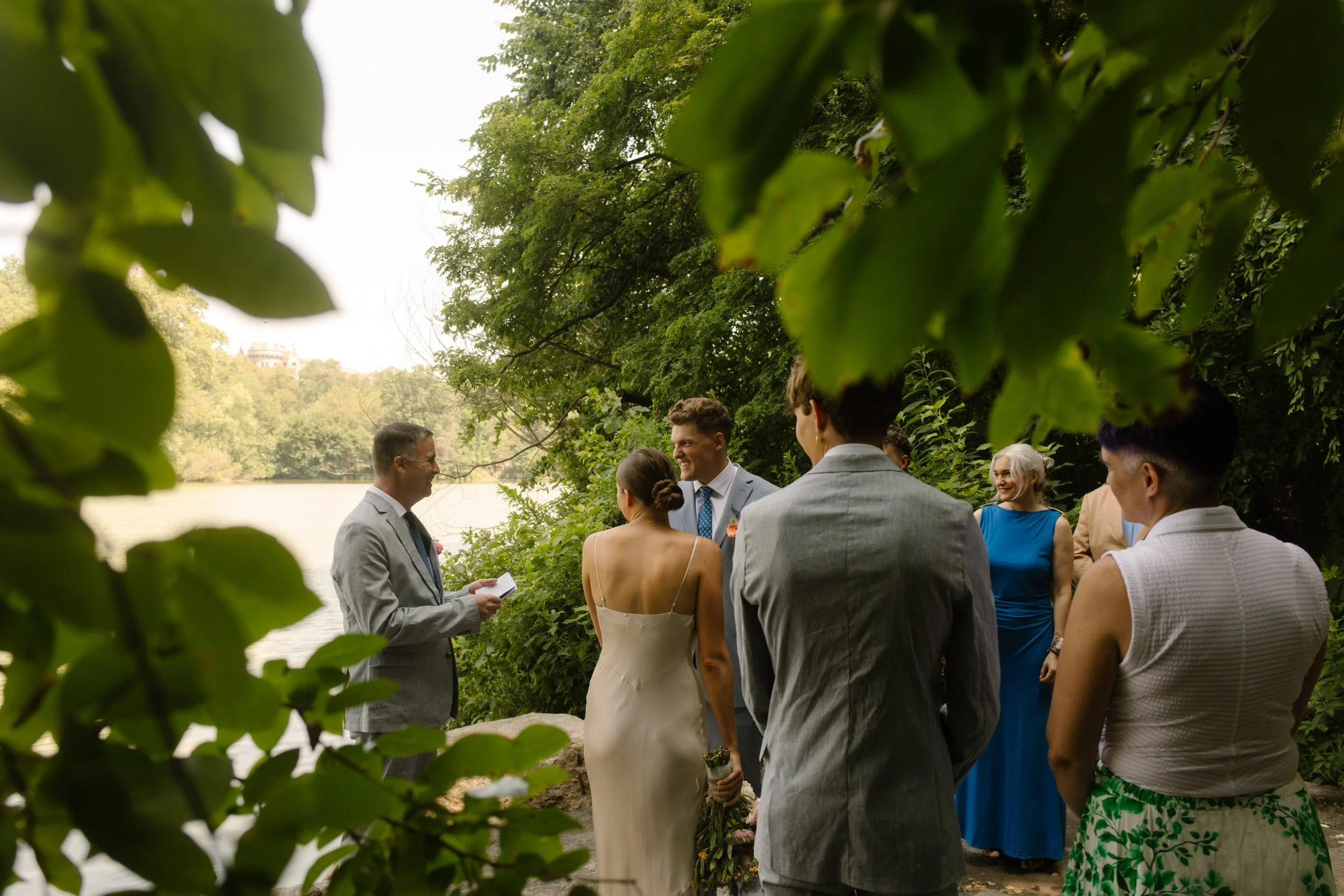 Intimate lakeside wedding ceremony in Central Park surrounded by family and lush greenery at one of the most scenic Wedding Locations in NYC.