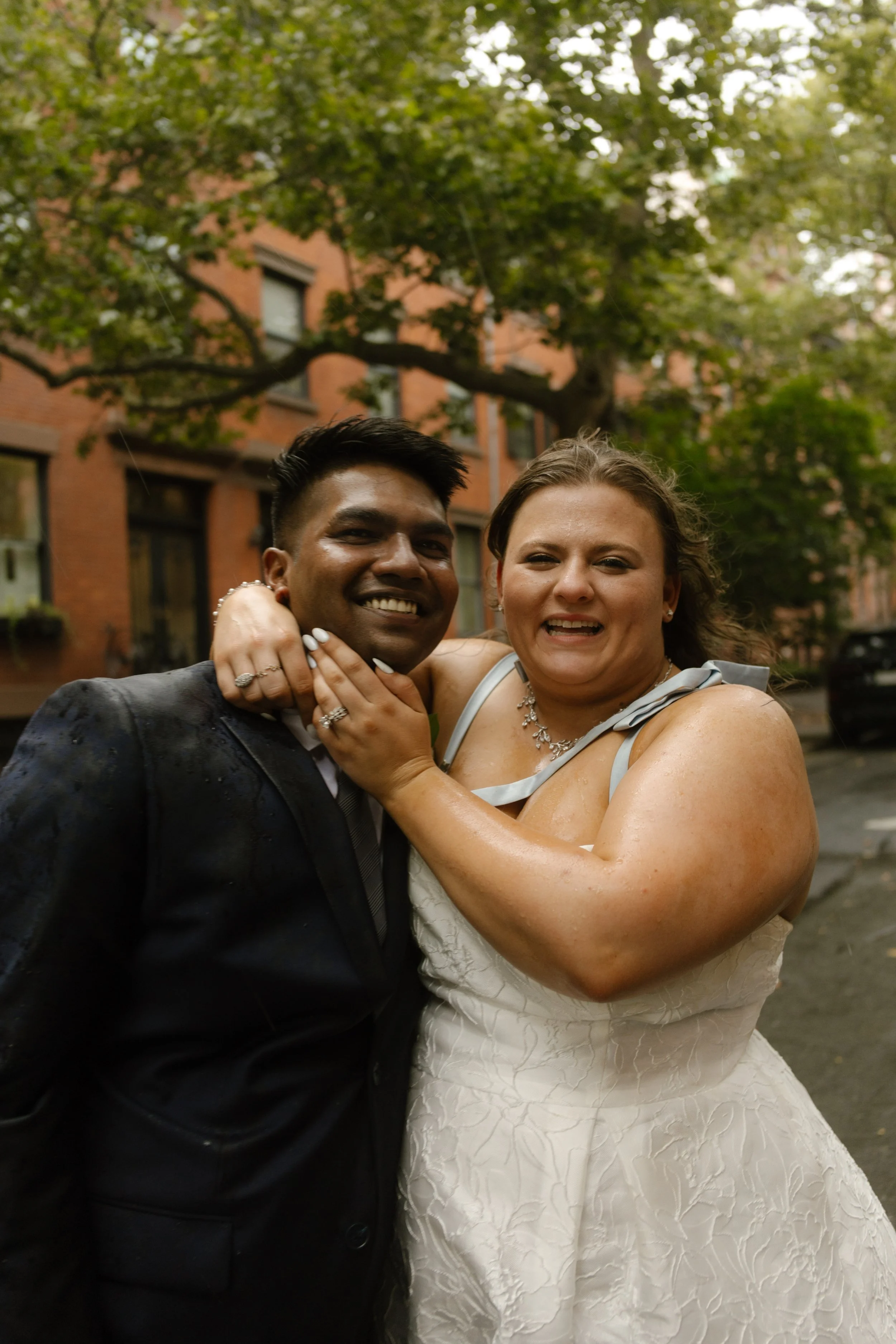 Bride hugs the groom while they smile together in the rain after their New York wedding ceremony.