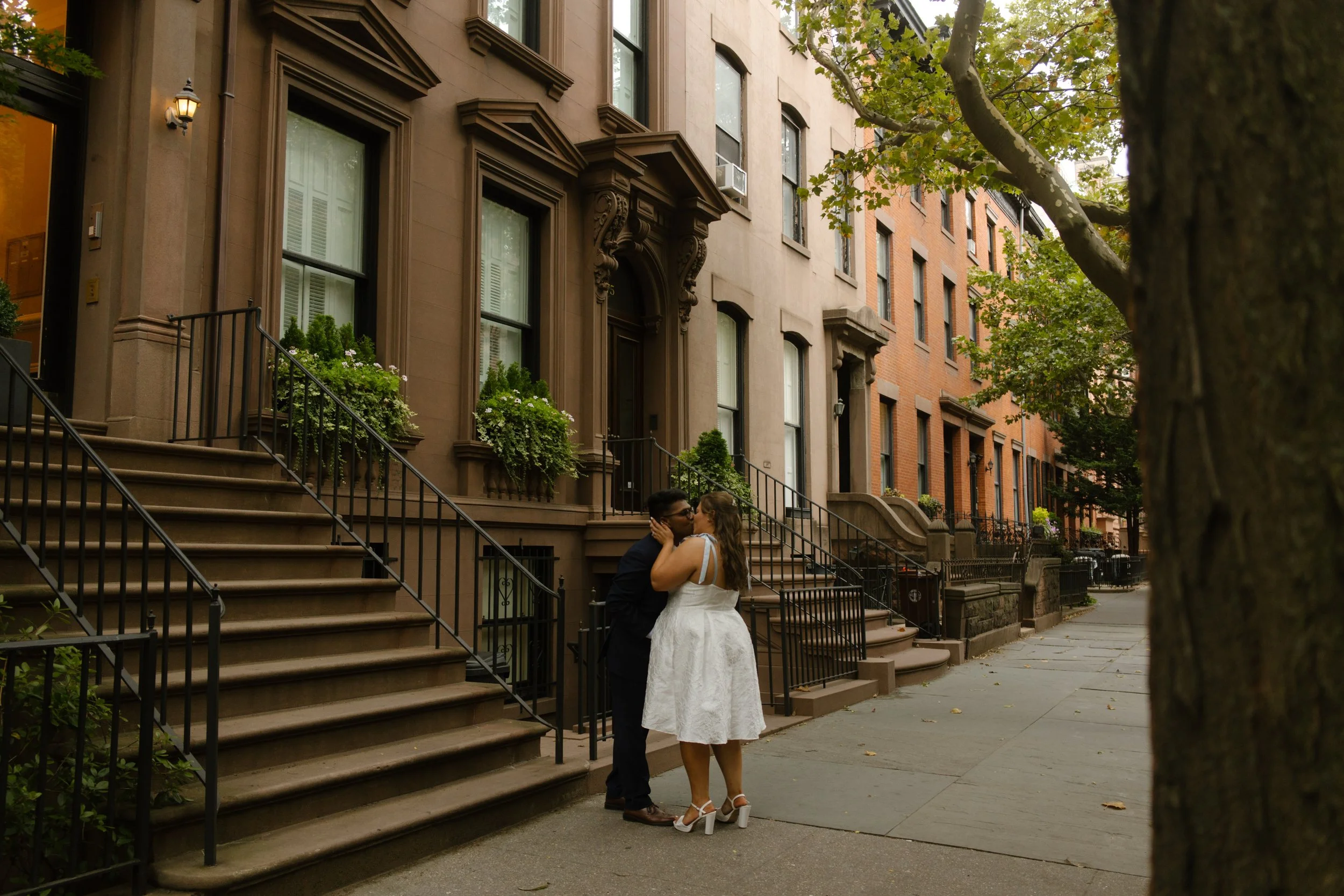 Couple kisses on the steps of a classic brownstone building, one of the charming Wedding Locations in NYC.