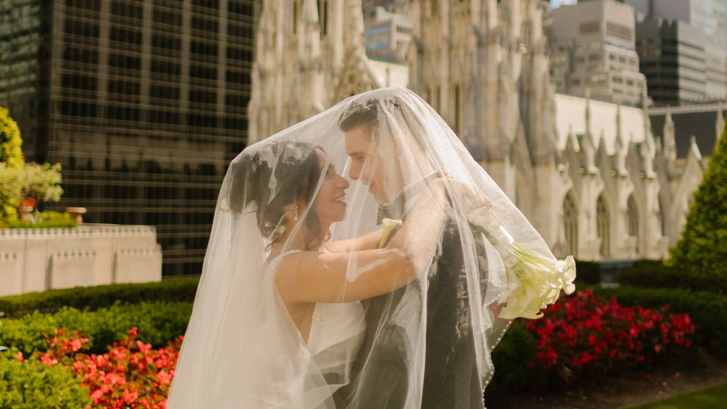 Bride and groom embrace beneath the wedding veil with St. Patrick's Cathedral creating a romantic backdrop at one of the most iconic Wedding Locations in NYC.