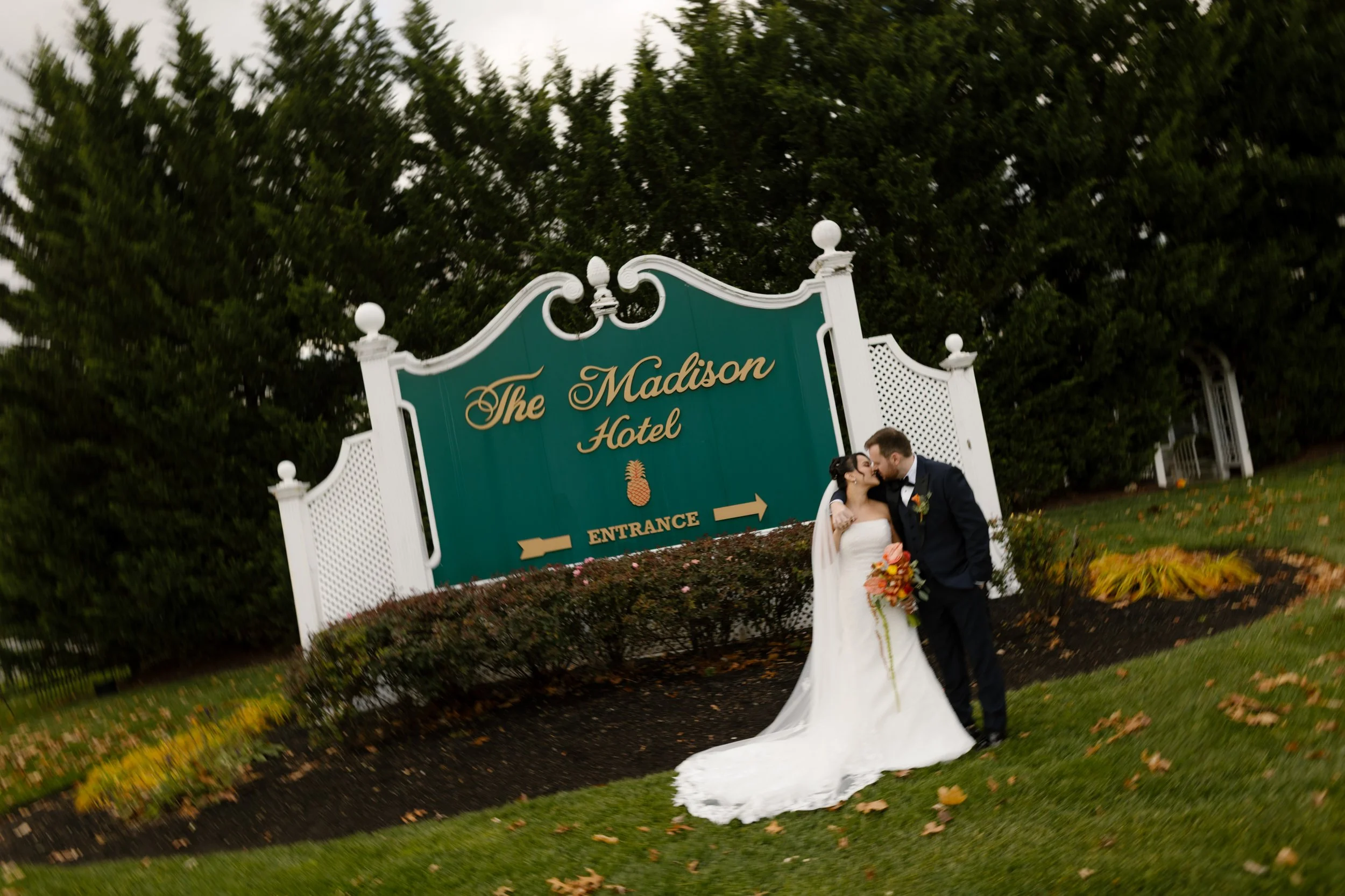 Bride and groom share a kiss in front of The Madison Hotel sign following their wedding ceremony.