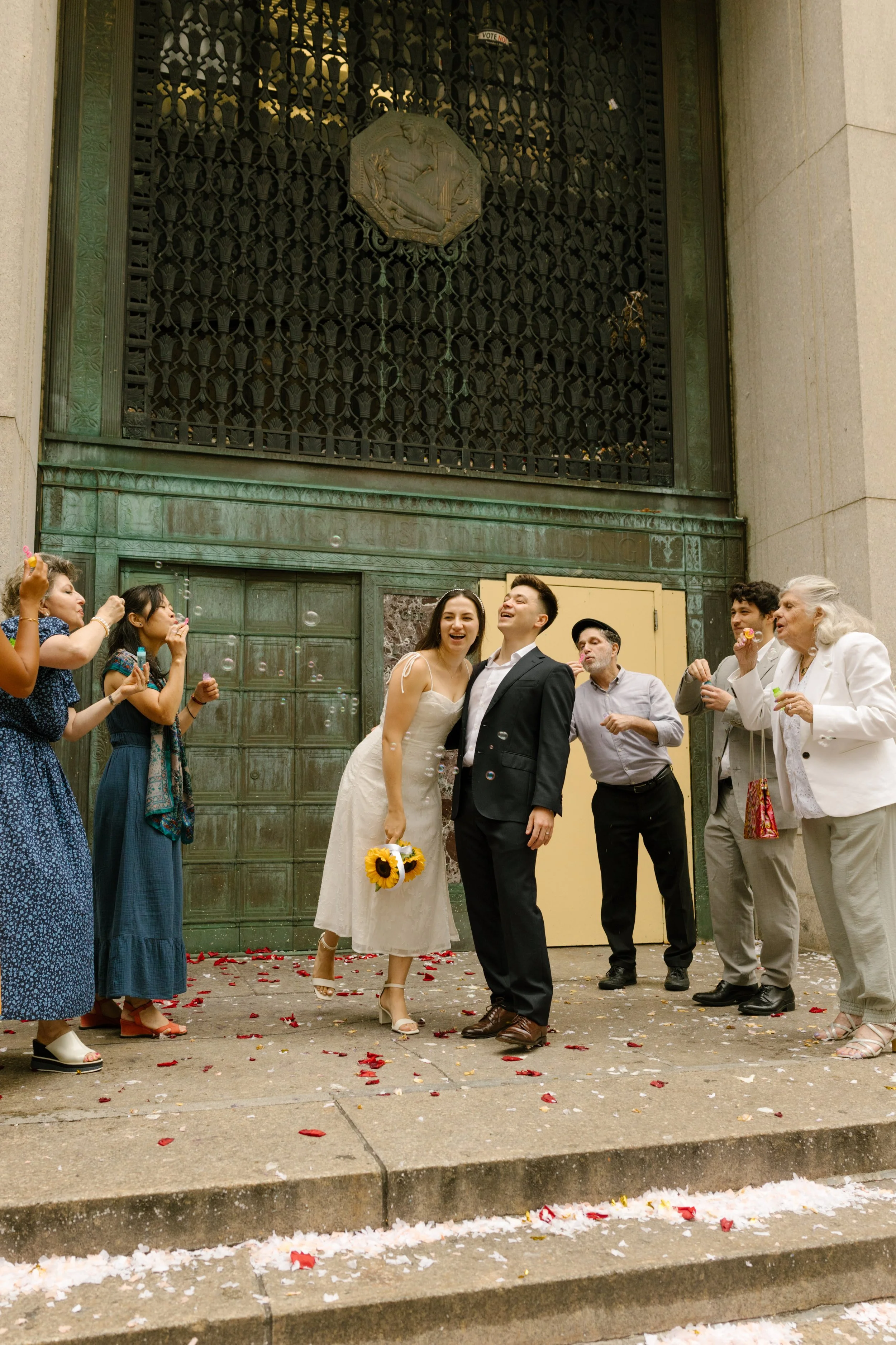 Newlyweds celebrate with family and friends outside a grand courthouse after their intimate Wedding Locations in NYC ceremony.