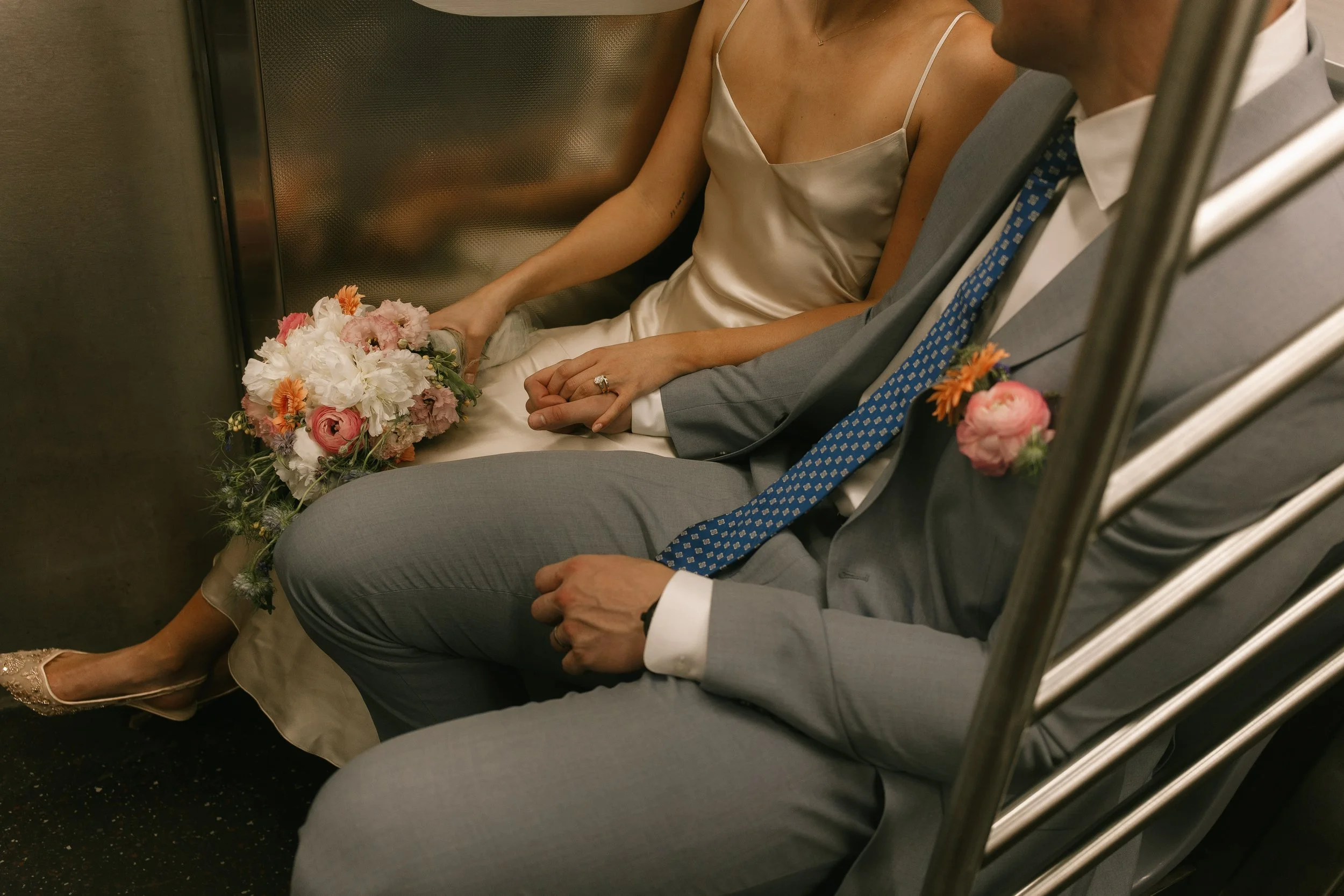 Newlyweds hold hands while riding the subway together after celebrating at iconic Wedding Locations in NYC.