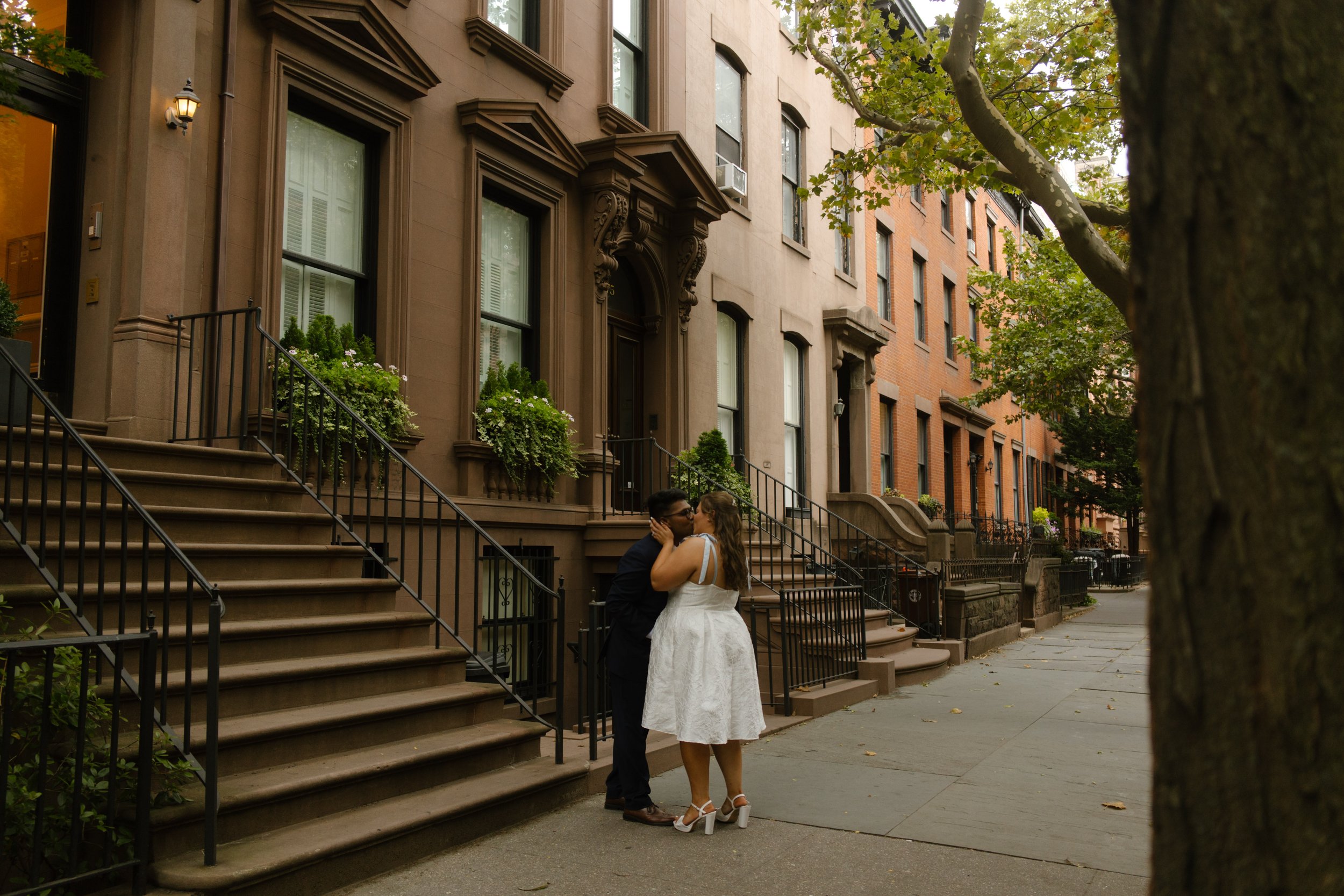 Couple kisses on a quiet brownstone-lined street, showcasing one of the most charming Wedding Locations in NYC for intimate portraits.