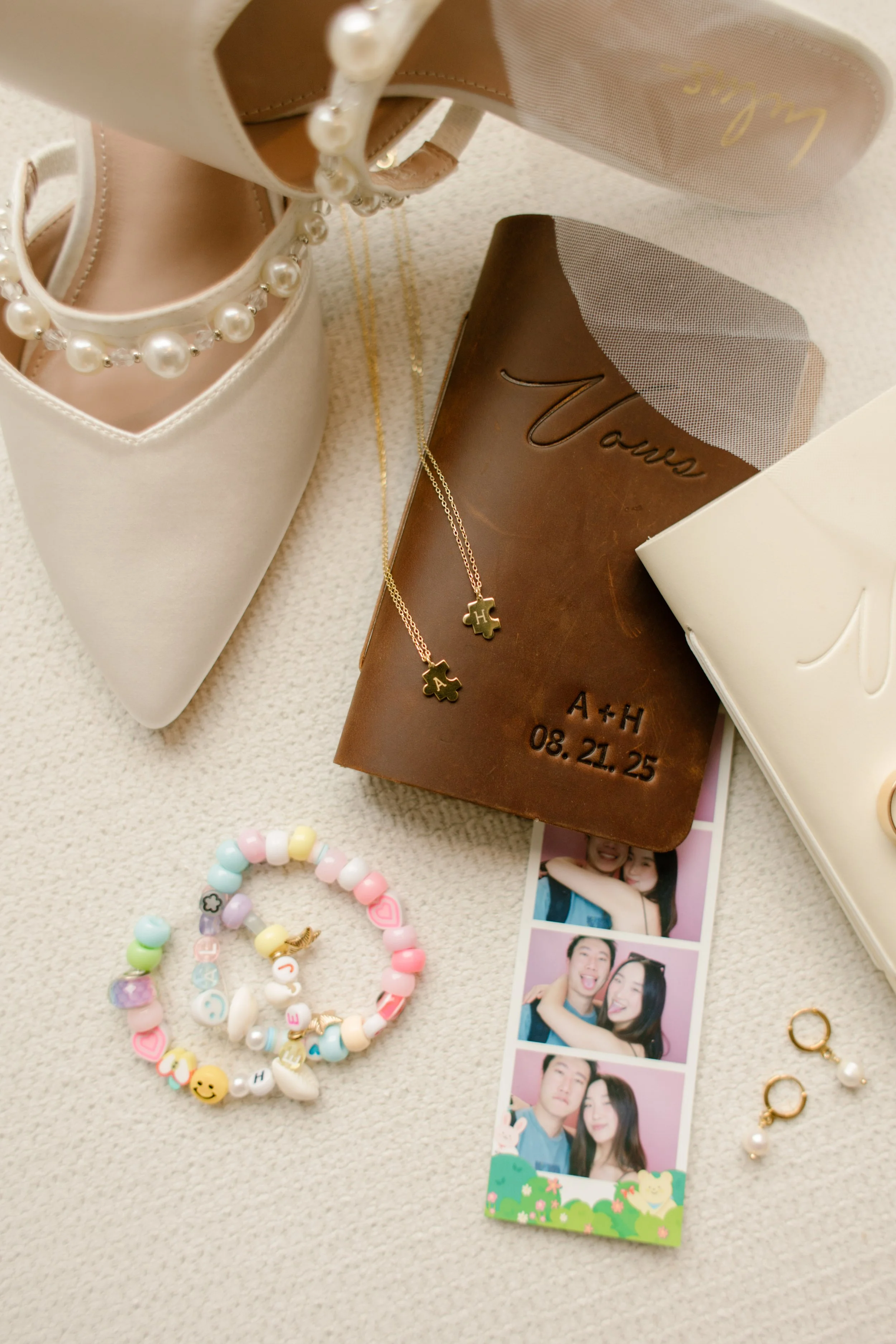 Flat lay of bridal accessories including pearl heels, personalized vows, jewelry, and keepsakes arranged before the wedding day.