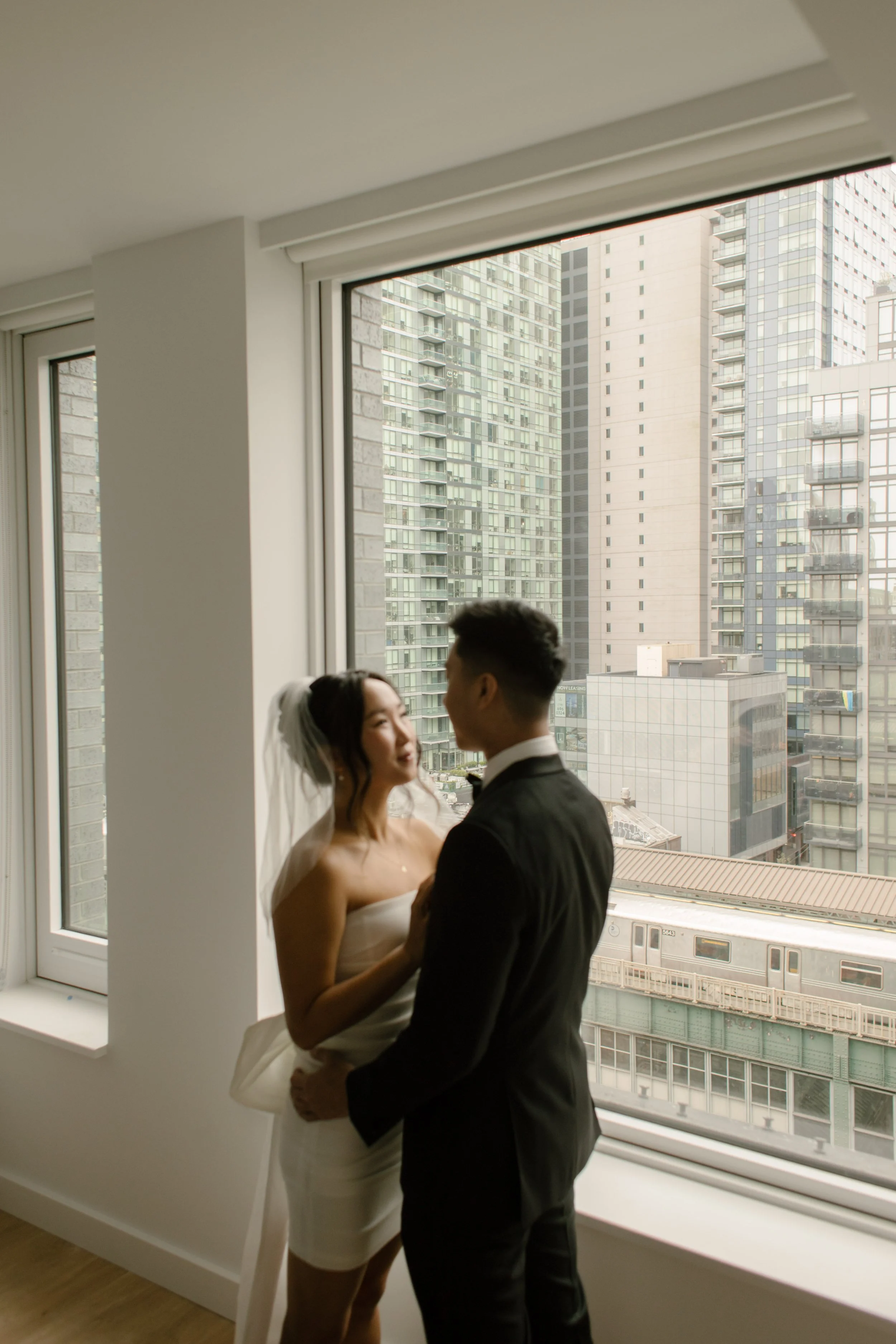 Bride and groom sharing a quiet moment by their apartment window before leaving for their wedding ceremony in Manhattan.