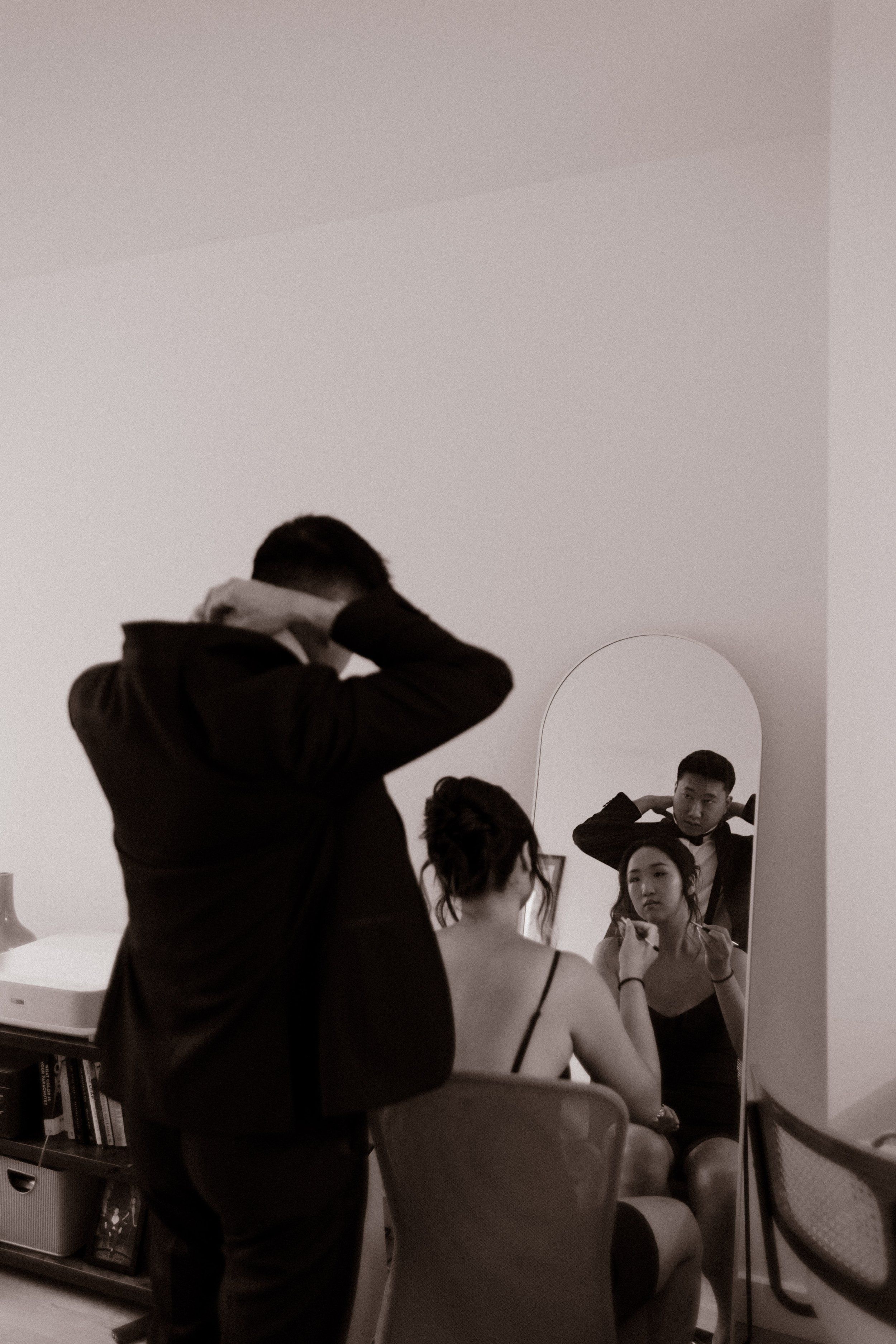 Bride and groom getting ready together in front of a mirror before their NYC courthouse wedding, sharing a quiet moment at home.