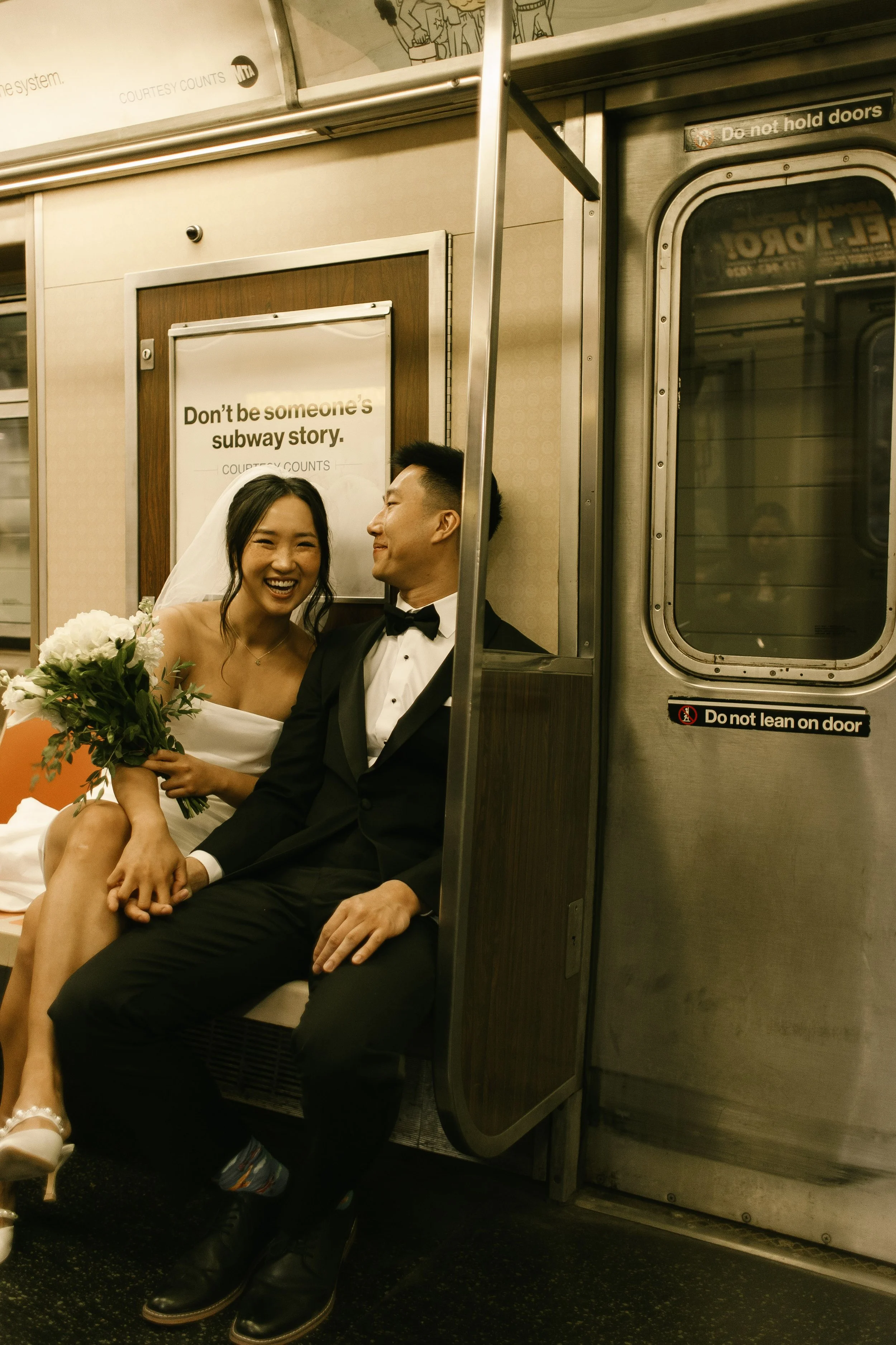 Newlyweds laughing together on the subway after their NYC courthouse wedding, embracing the city's everyday rhythm.