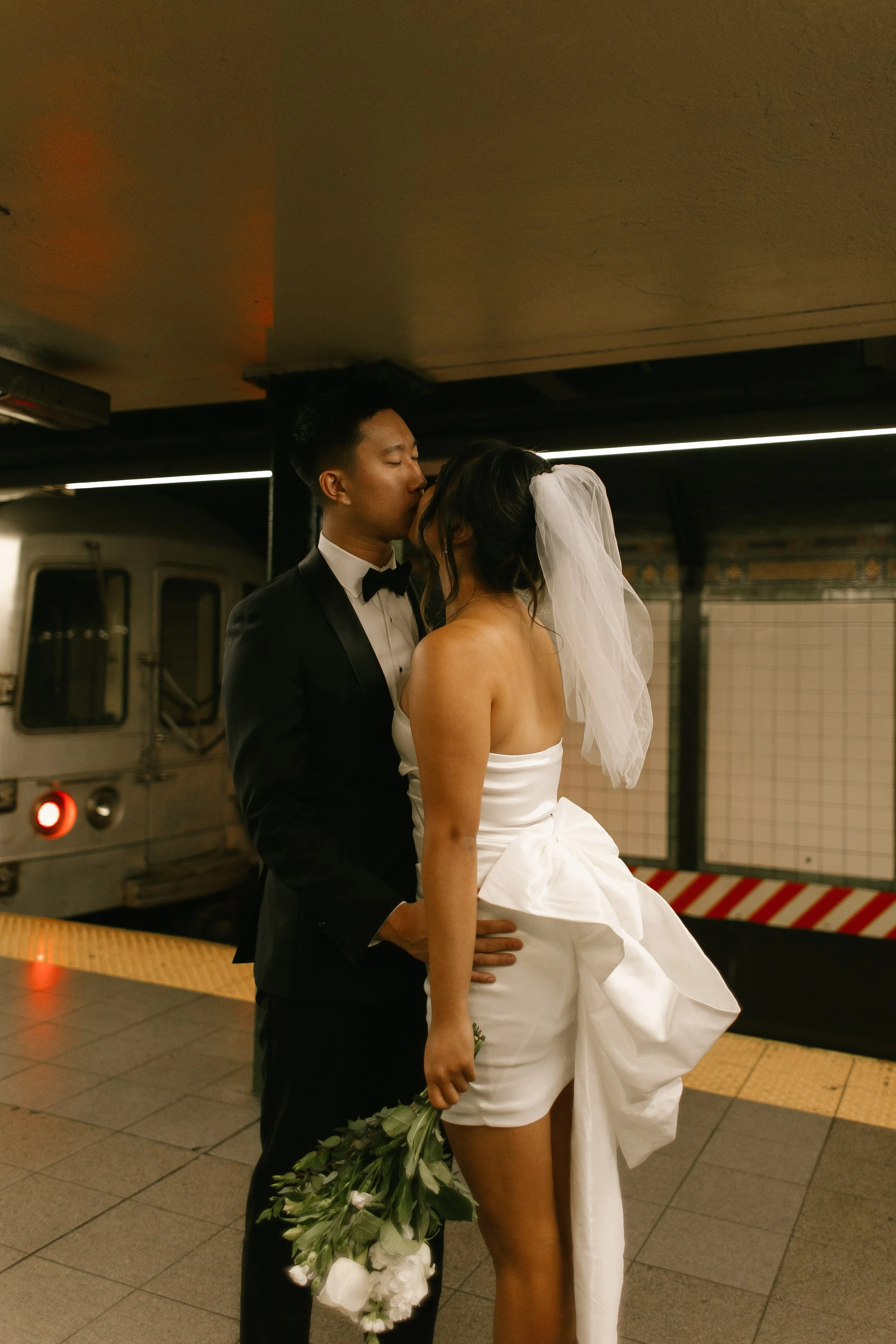 Bride and groom share a kiss on a subway platform following their nyc courthouse wedding.