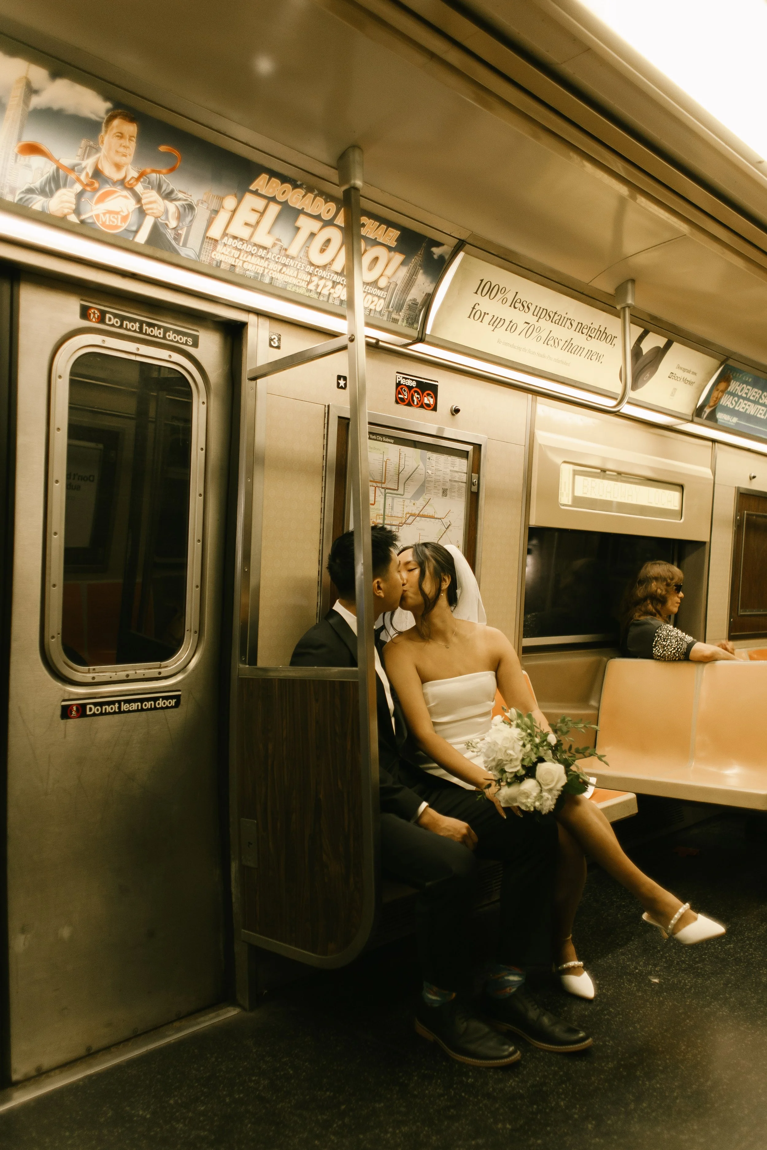 Couple kisses while riding the NYC subway after their courthouse wedding ceremony.