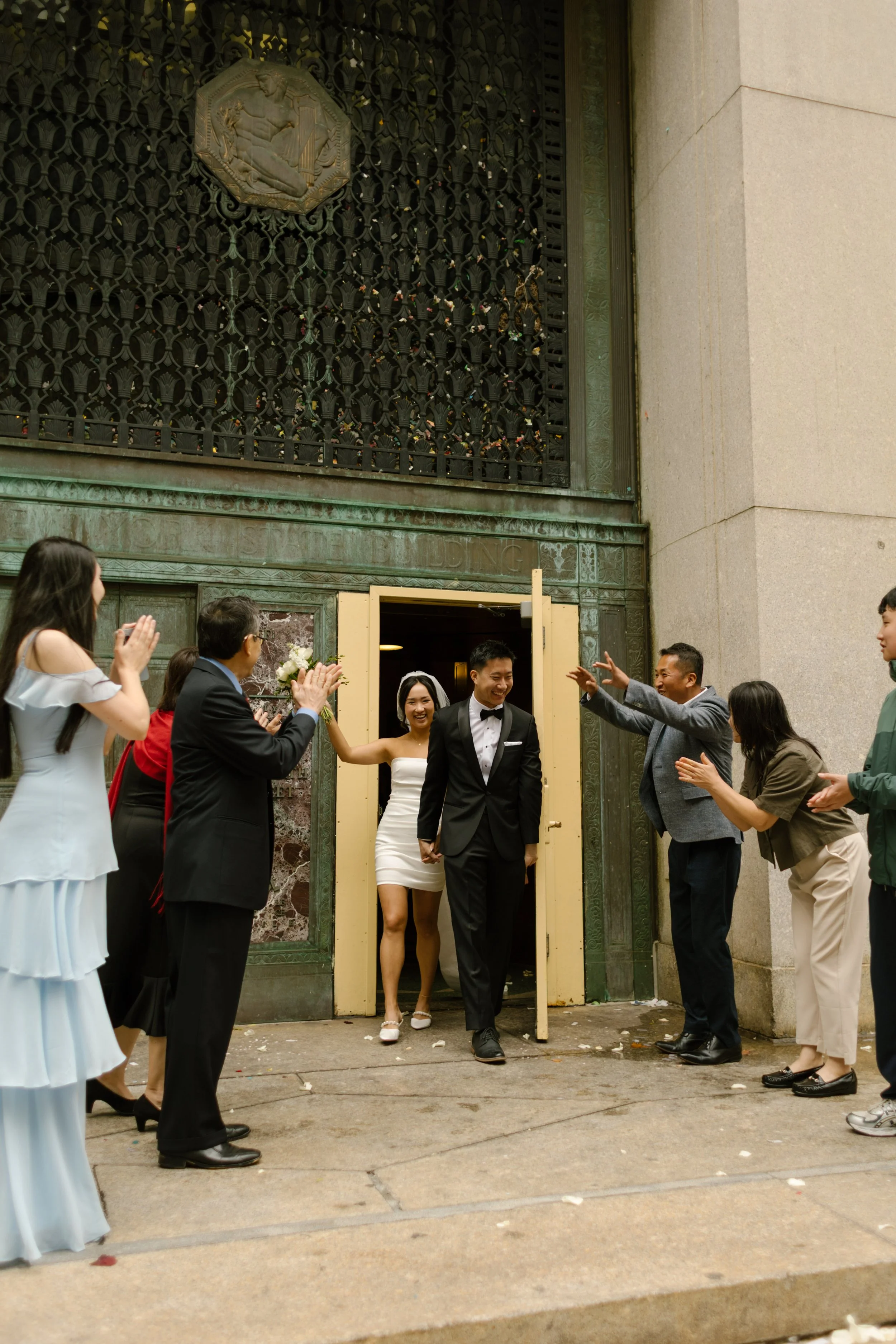Family cheers as the newly married couple exits the courthouse holding hands in downtown Manhattan.