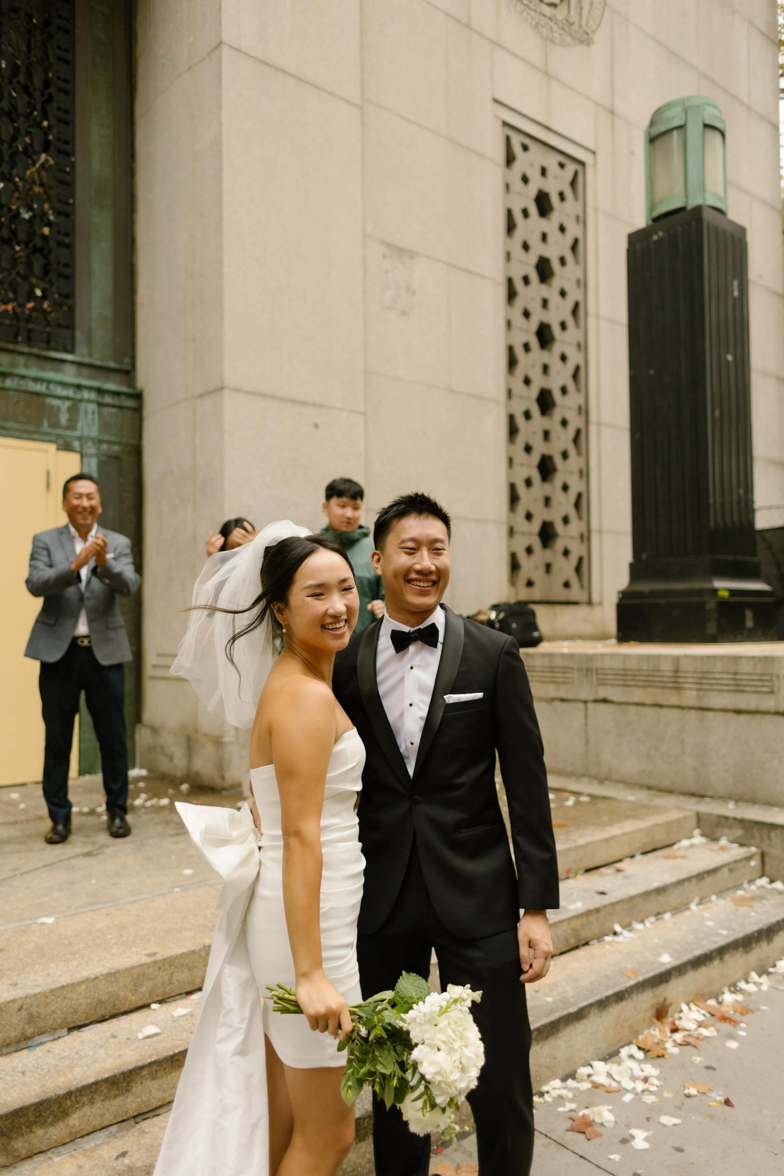Smiling newlyweds pose outside the courthouse moments after their intimate New York City wedding ceremony.
